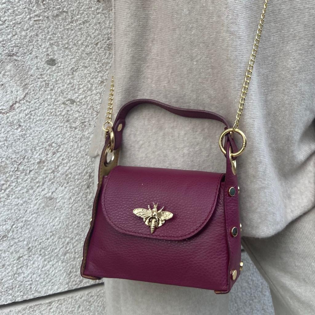 Mala pequena de pele vinho com abelha metálica dourada e corrente dourada