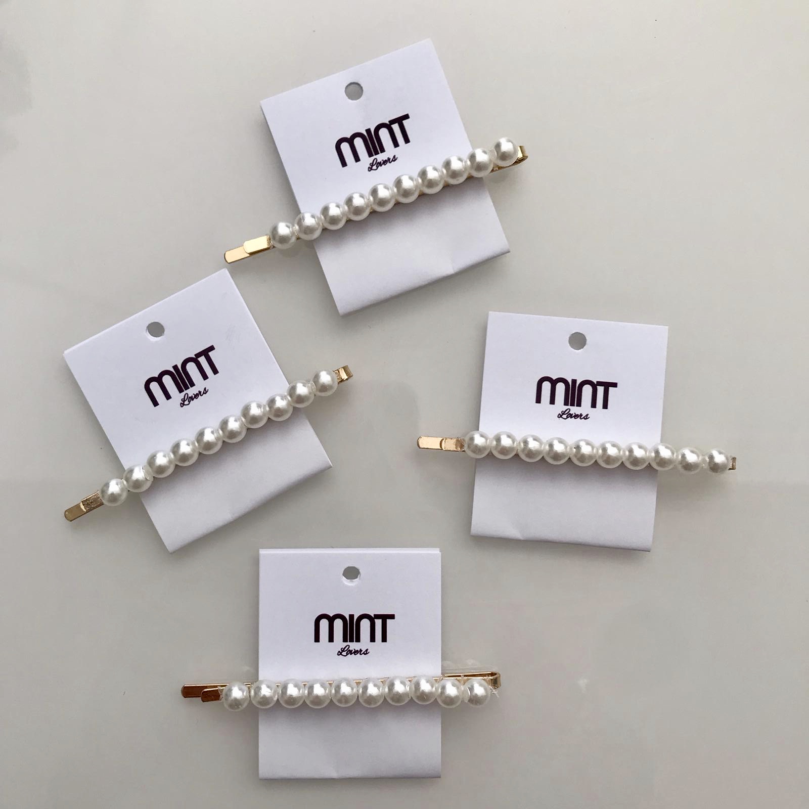 Presilhas de cabelo douradas com pérolas em cartões brancos da marca MINT STORE