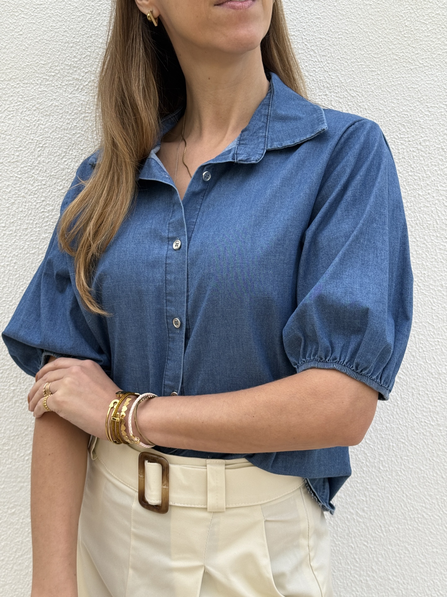 Blusa azul denim com botões e calças bege com cinto e fivela