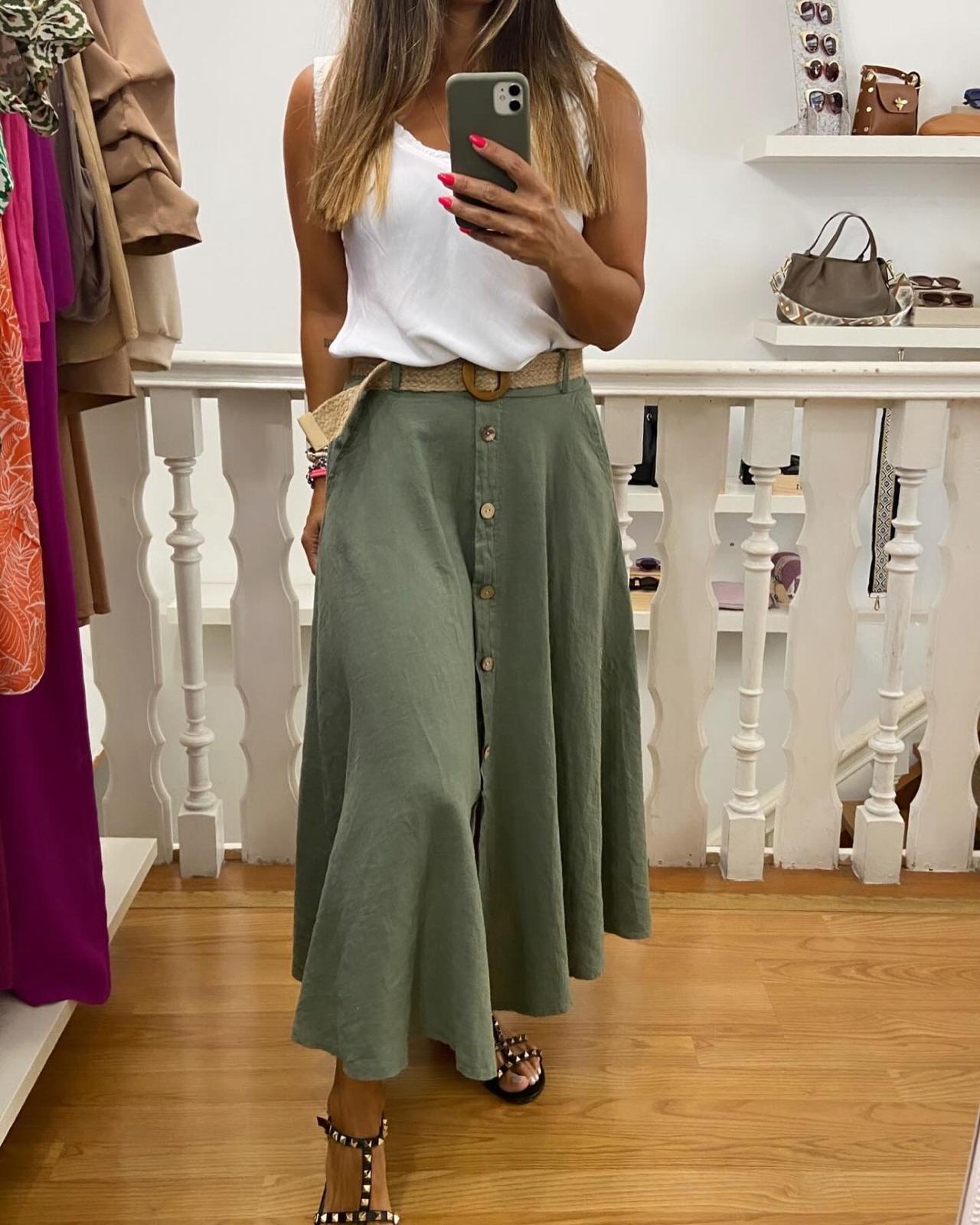 Saia midi verde clara com botões e cinto, camisa branca sem mangas e sandálias pretas em ambiente interior