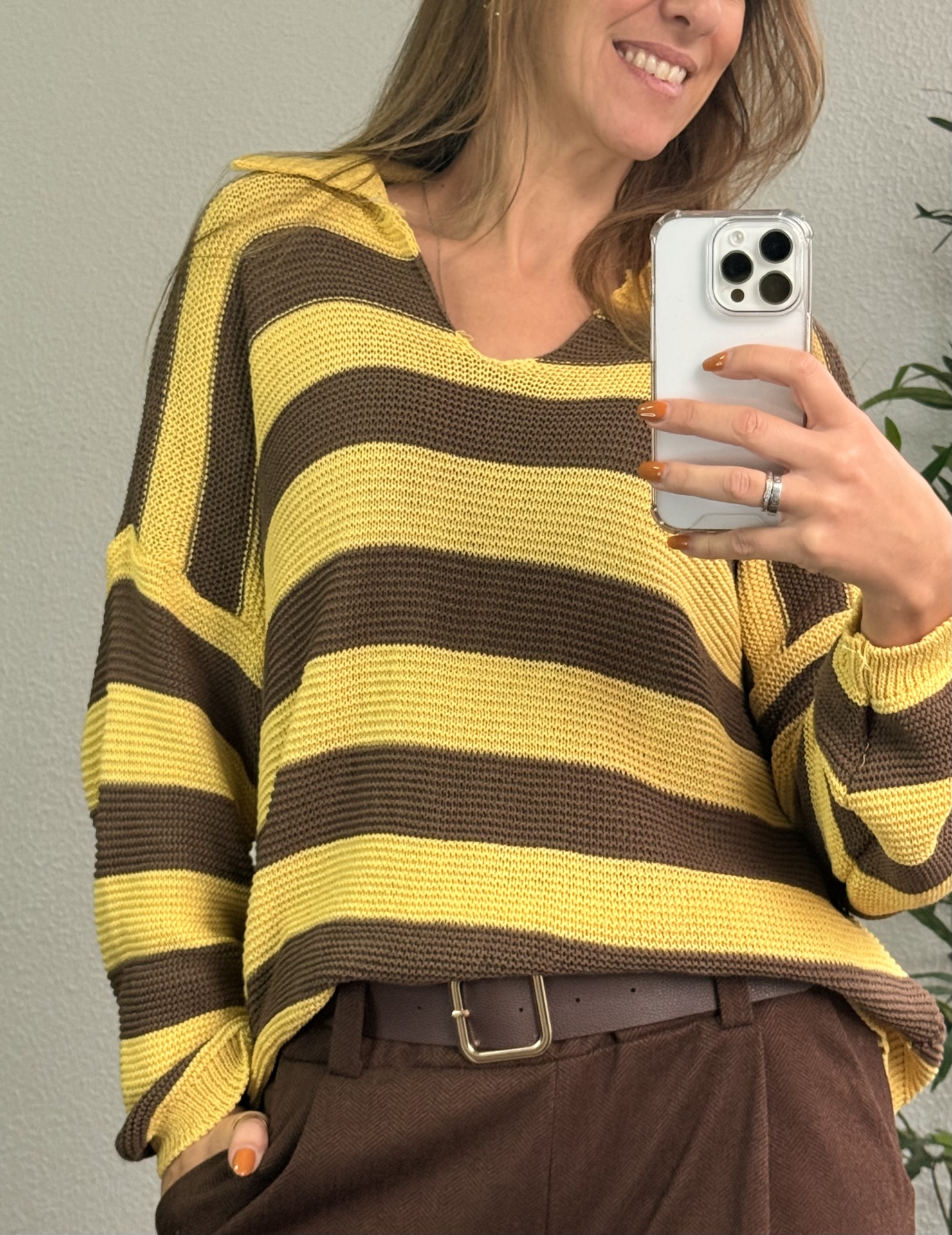Camisola riscas amarelo e castanho com gola em V usada por mulher com calças e cinto castanho.