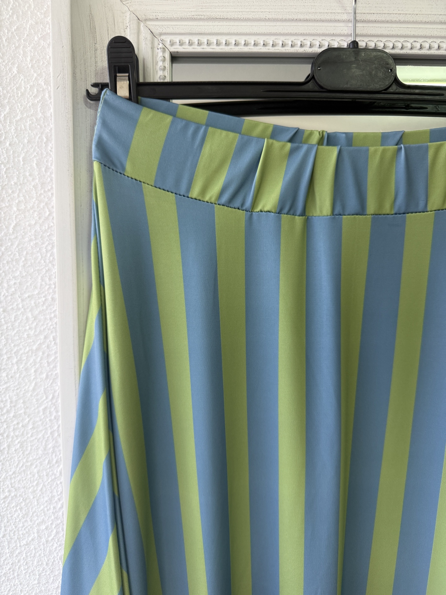 saia de riscas verticais azul e verde pendurada num cabide
