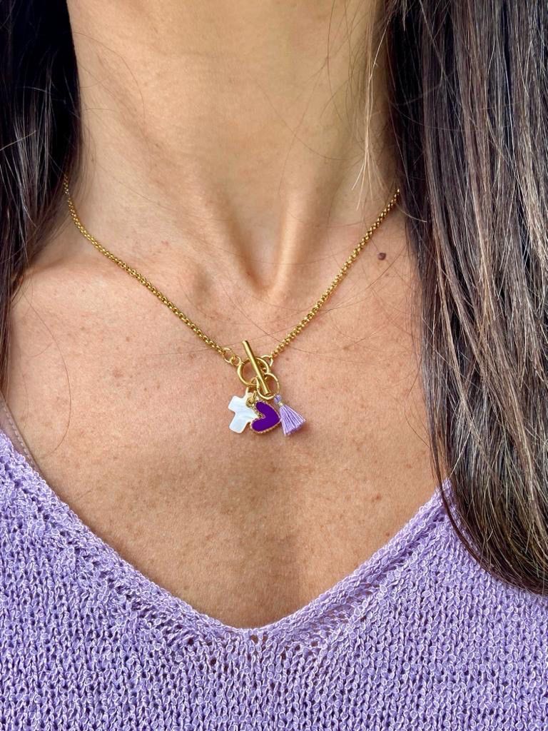Colar dourado com pendentes roxo, branco e lilás em pescoço com camisola lilás