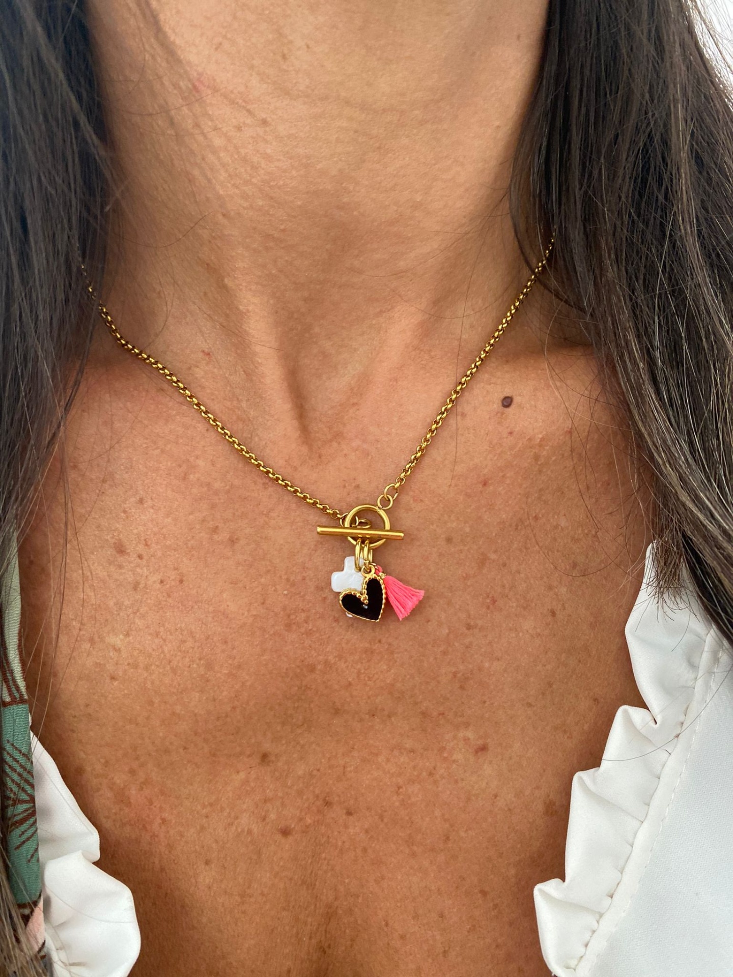 Colar dourado com pendentes em formato de coração preto, símbolo branco e pendente rosa com corrente e fecho de argola e barra