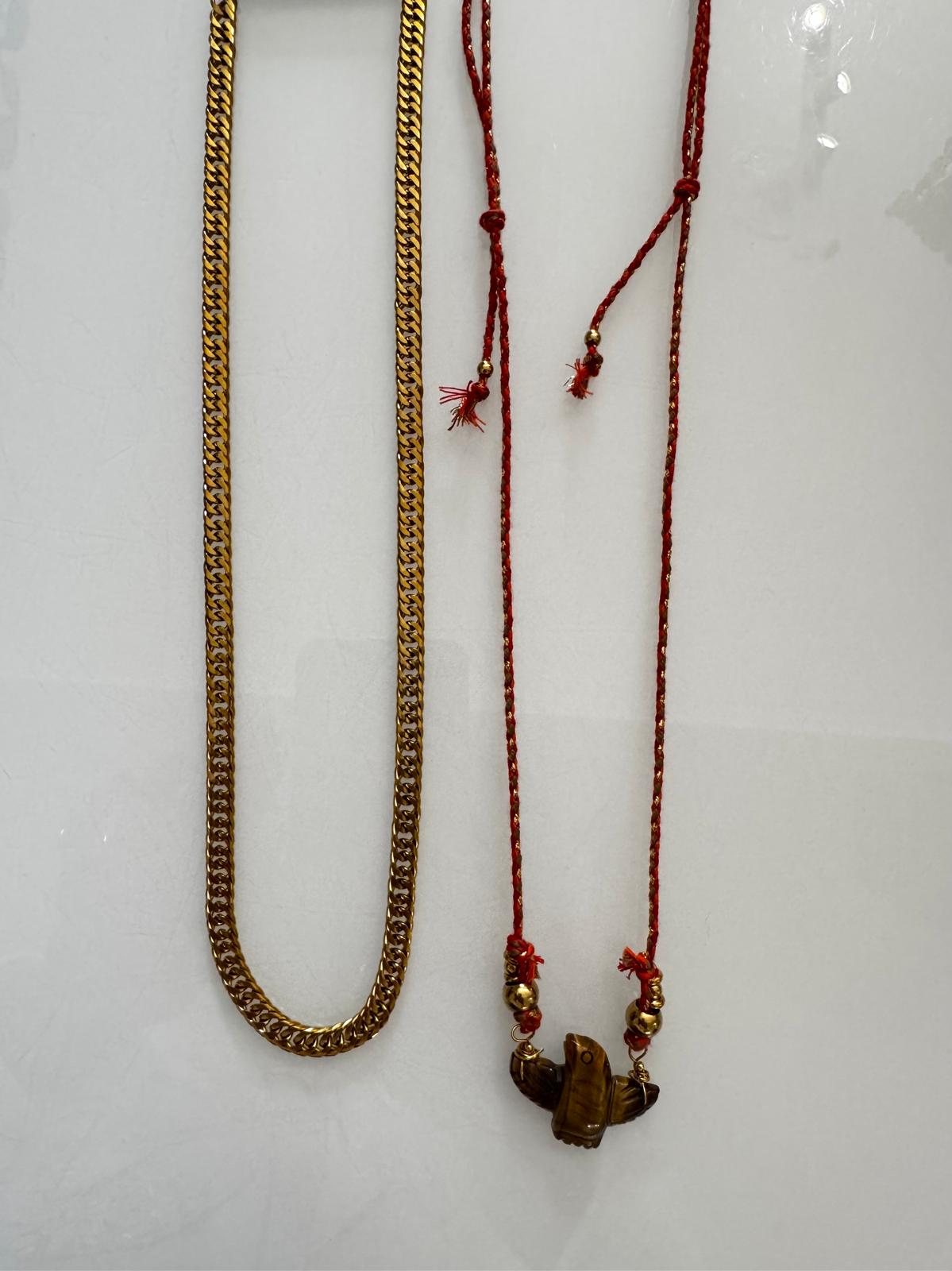 Dois colares, um dourado em corrente e outro com cordão vermelho e pendente castanho