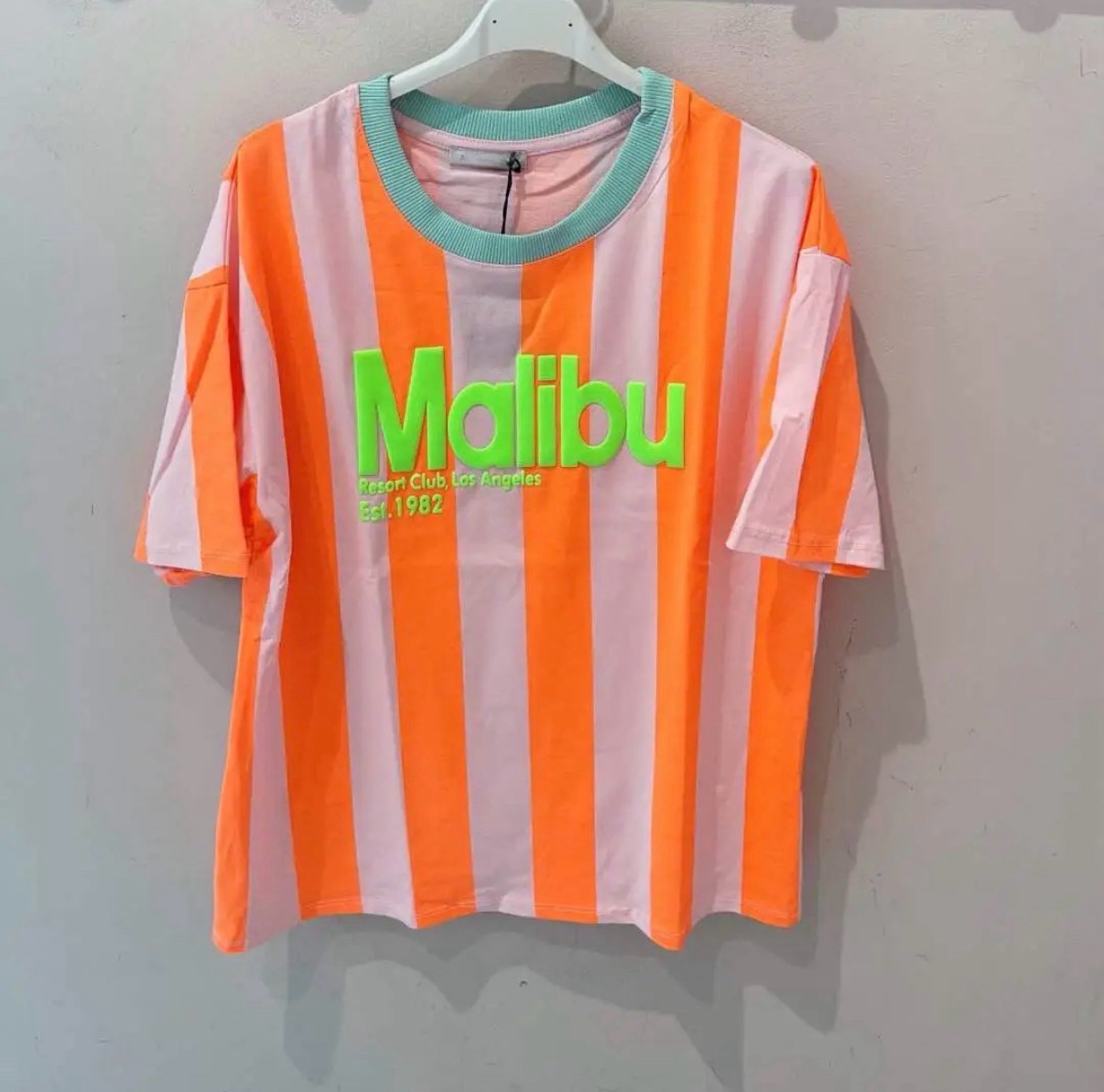 T-shirt riscada rosa e laranja com texto Malibu em verde neon
