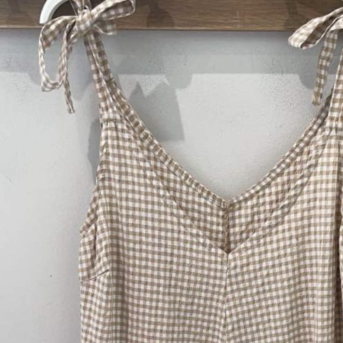 Vestido xadrez bege e branco com alças de laço pendurado num cabide