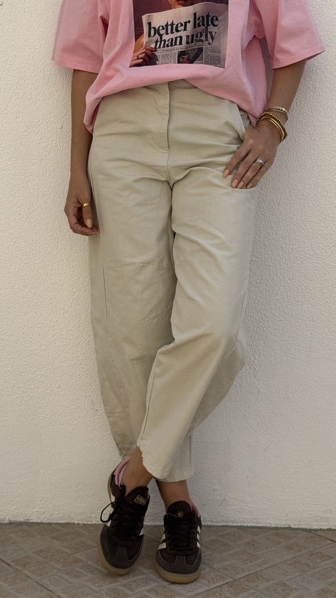 Calças bege largas, t-shirt rosa estampada e ténis pretos com detalhes brancos