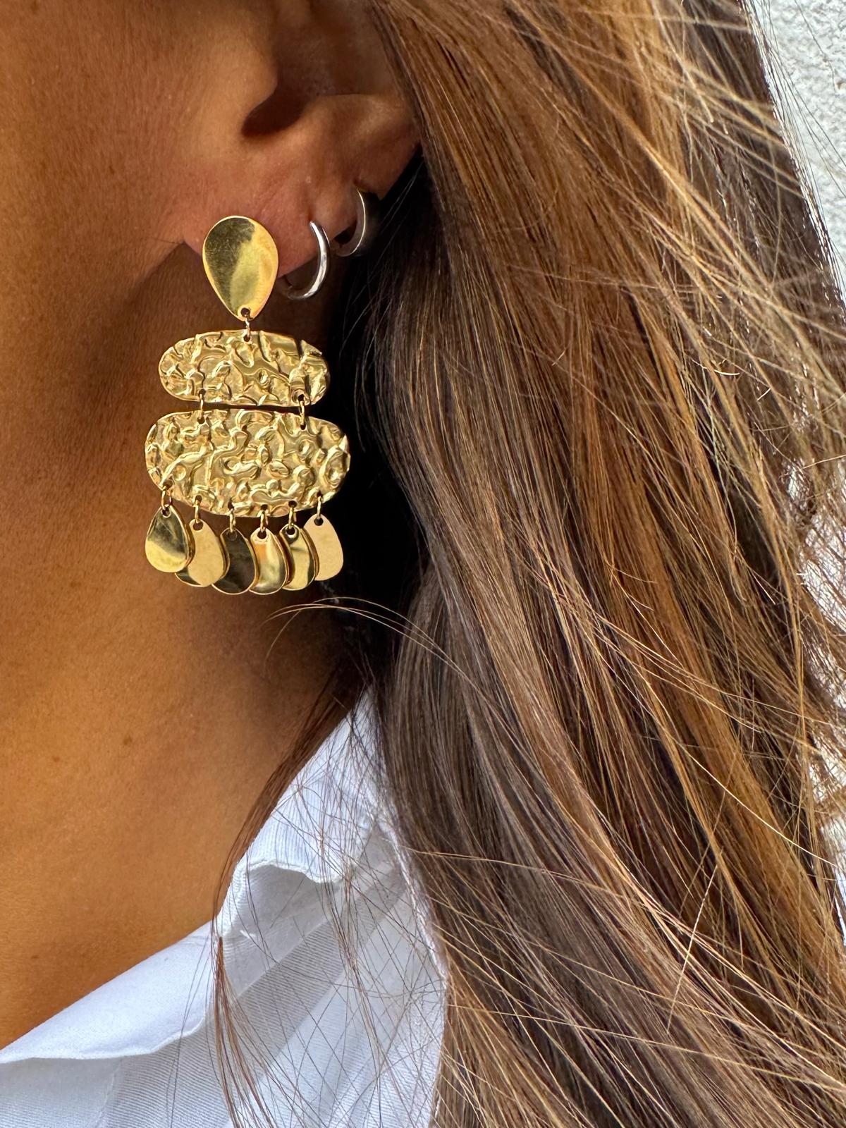 Brinco de ouro com diferentes texturas usado em orelha feminina