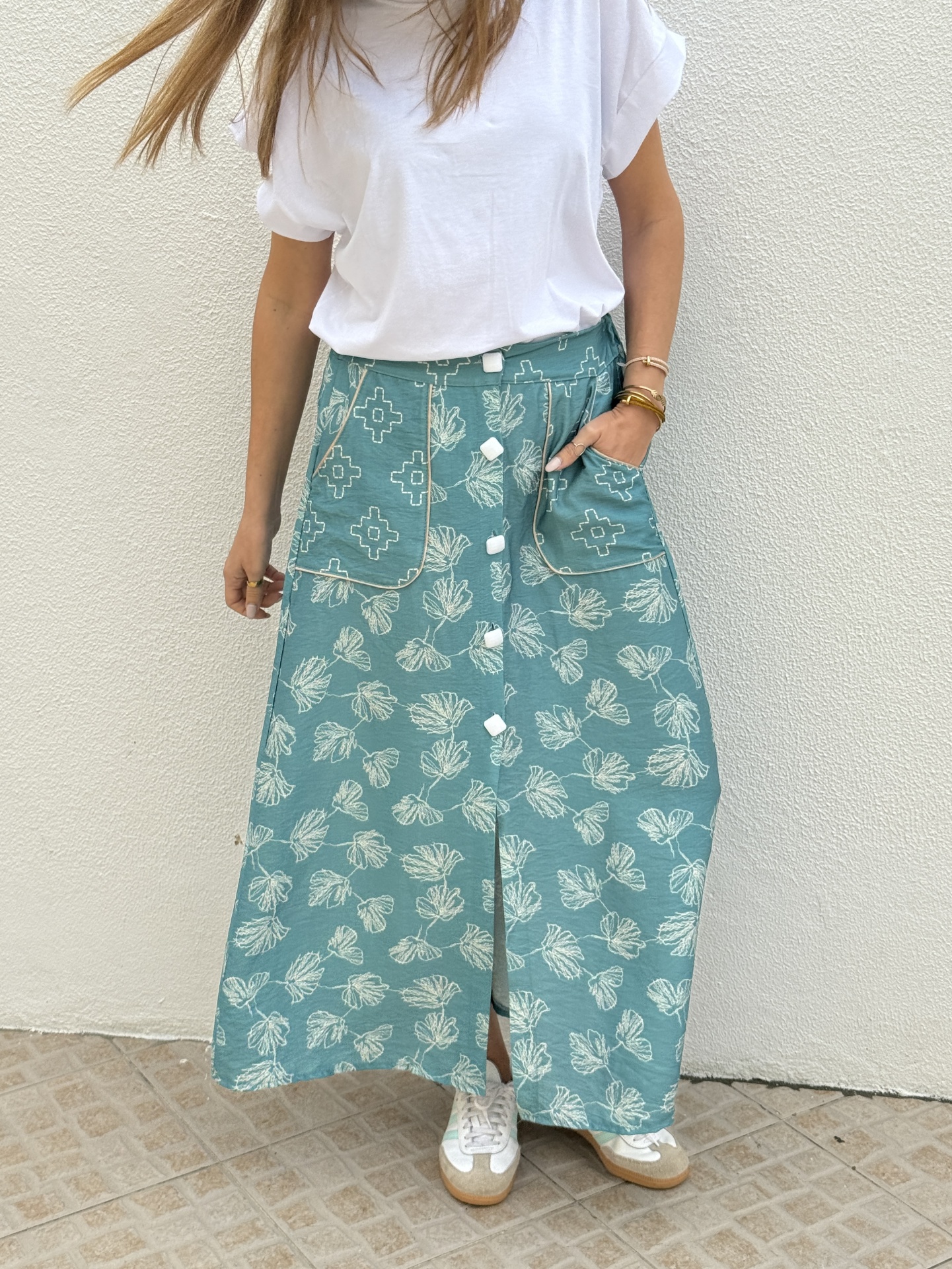 Saia longa azul com estampa de folhas e botões brancos ao centro