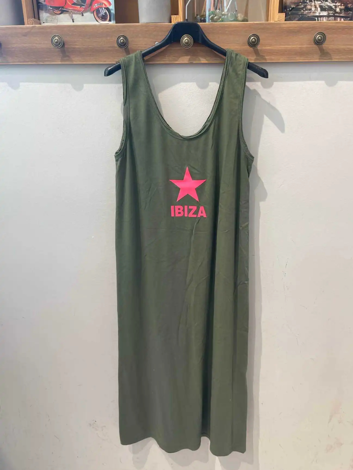 Vestido longo verde oliva com estampa rosa de estrela e IBIZA pendurado na parede