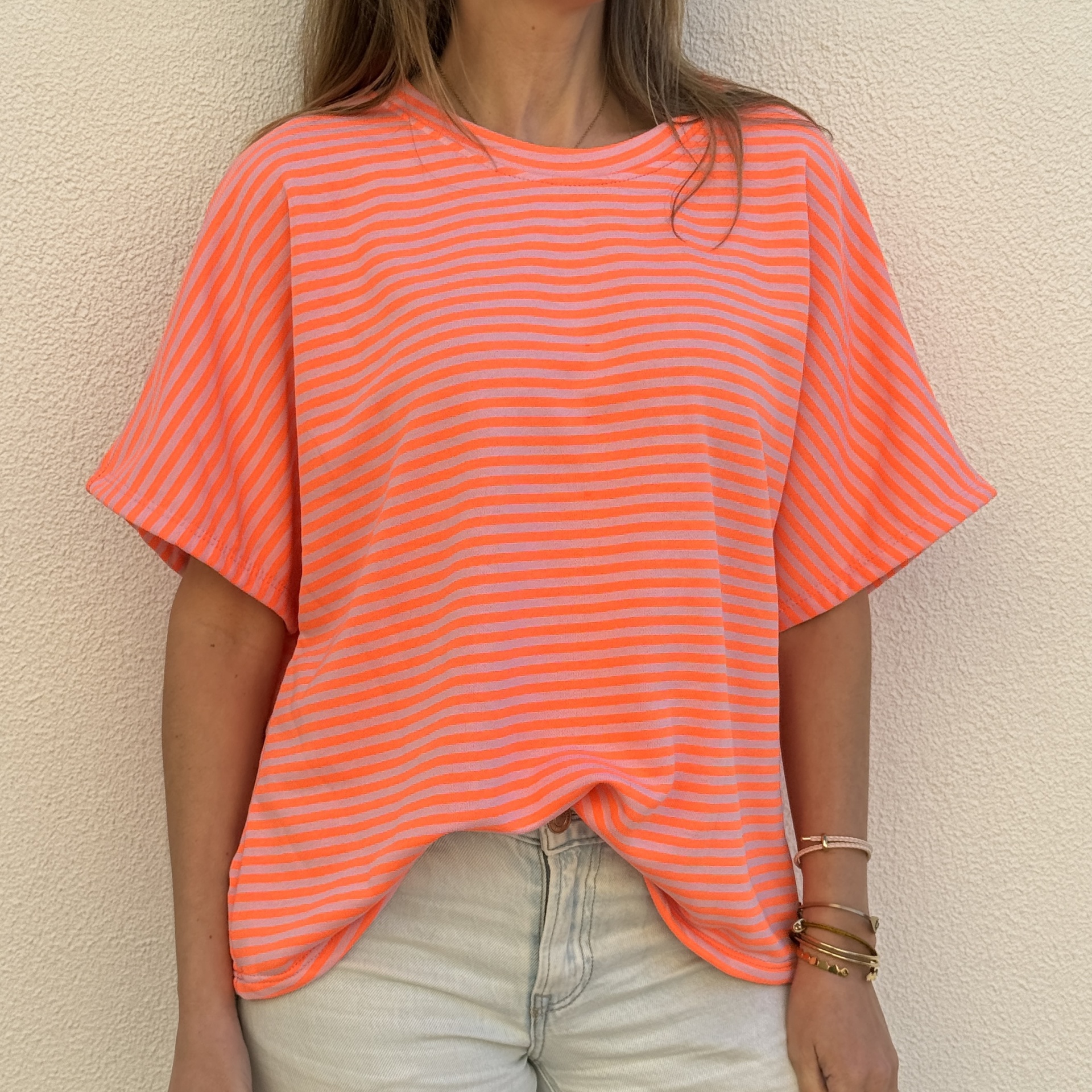 Camisola riscada laranja e rosa com calças claras