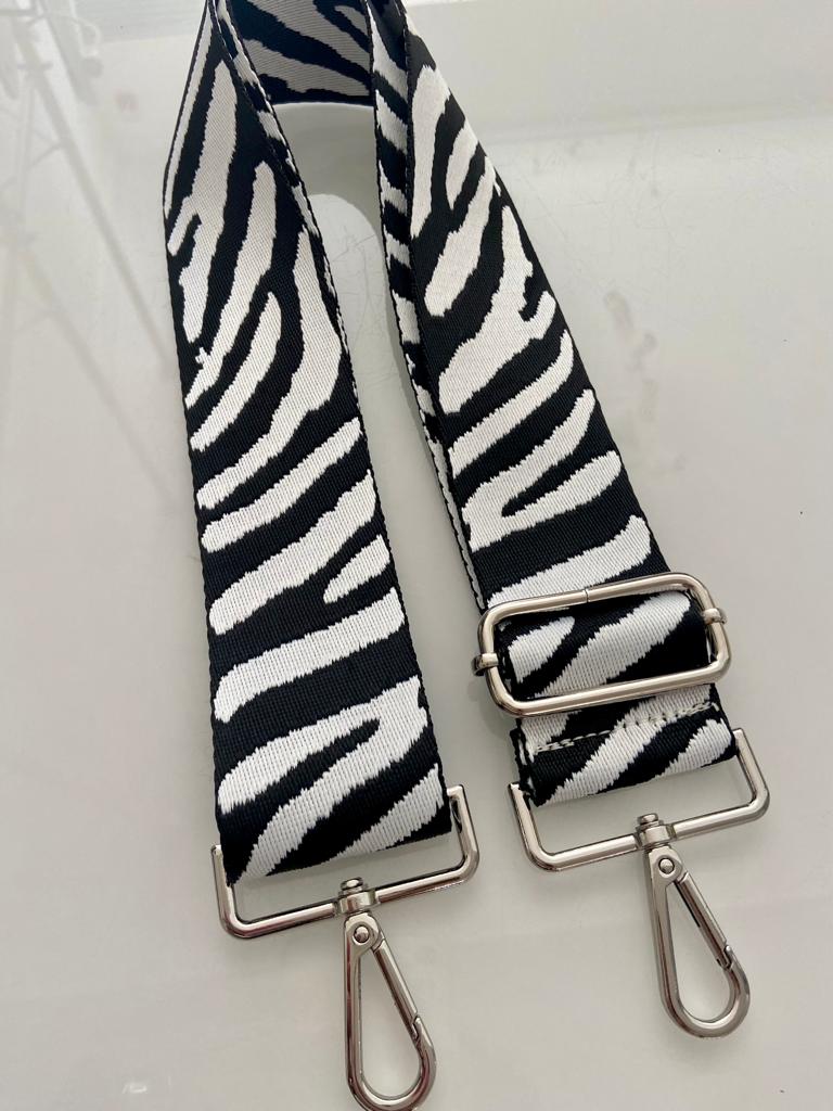 Alça de tecido preta e branca com padrão animal e fivelas metálicas