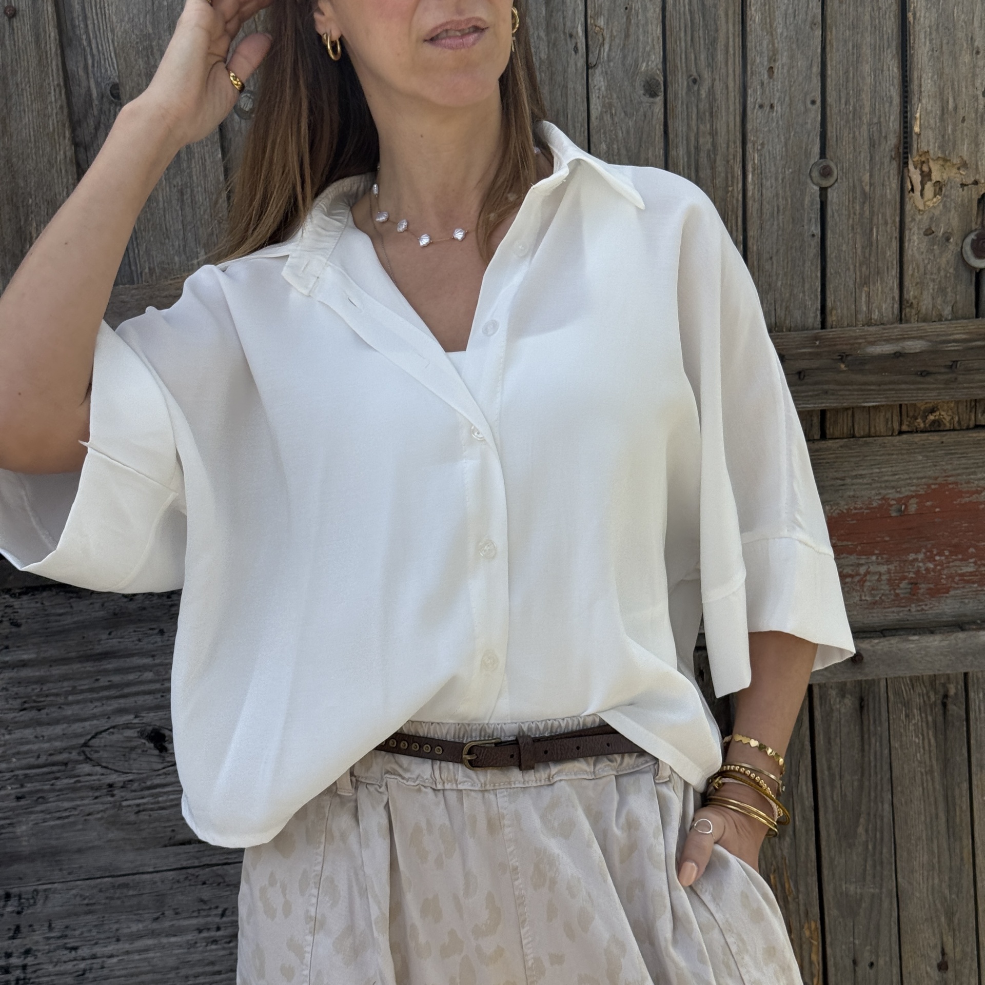 Blusa branca com botões e saia bege estampada combinadas.