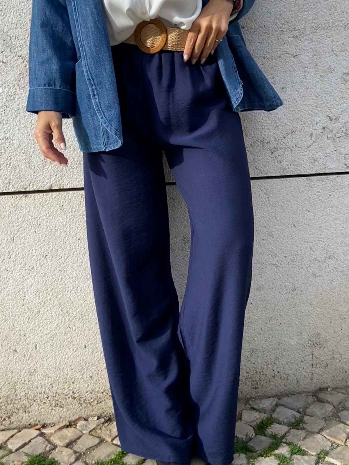 Calças largas azul-marinho com cinto castanho de palha e camisa de ganga azul