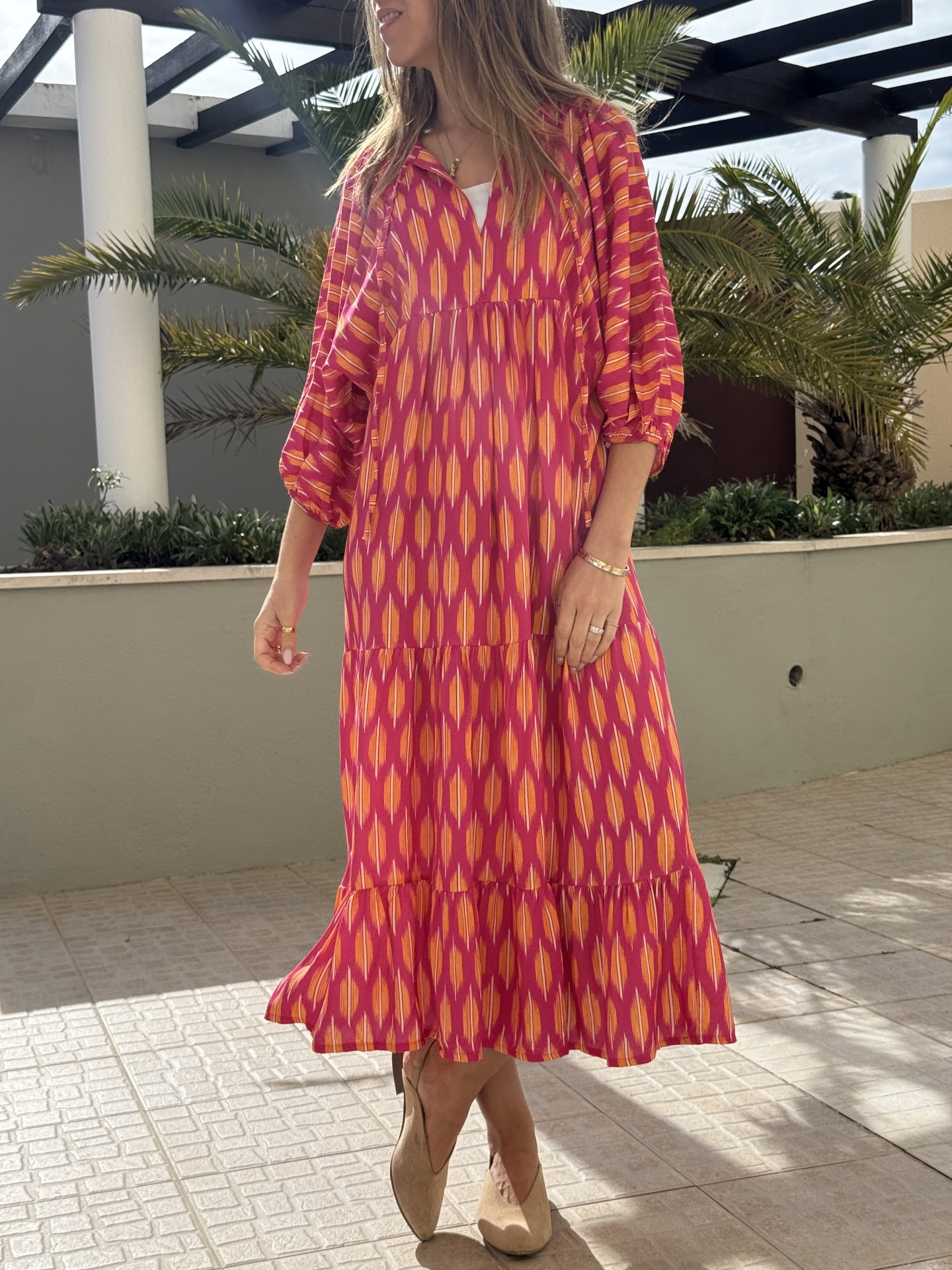 Vestido comprido rosa e laranja com padrão geométrico, mangas 3/4 e tecido leve.