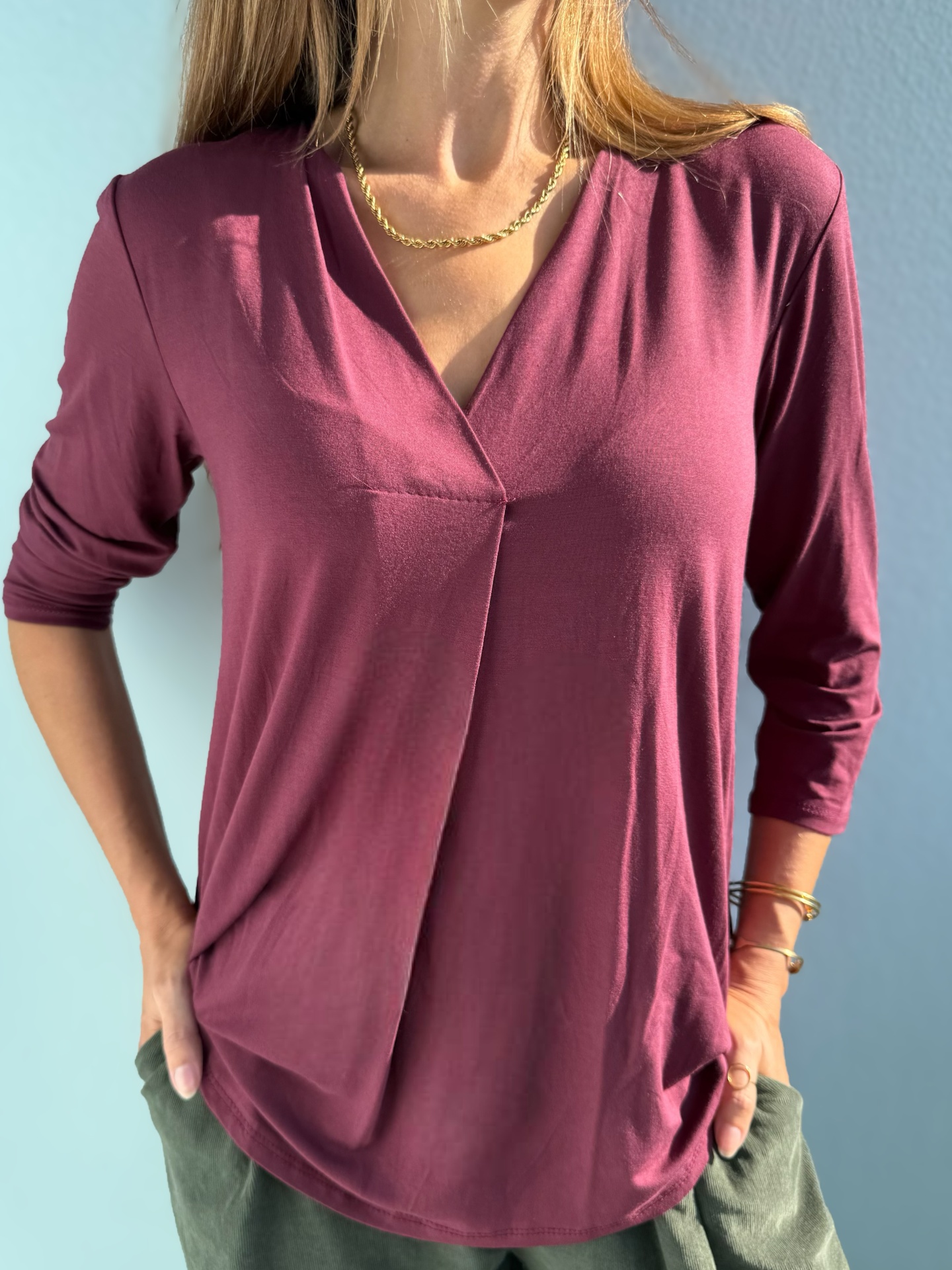 Camisola borgonha de manga comprida com decote em V e franjas centrais.