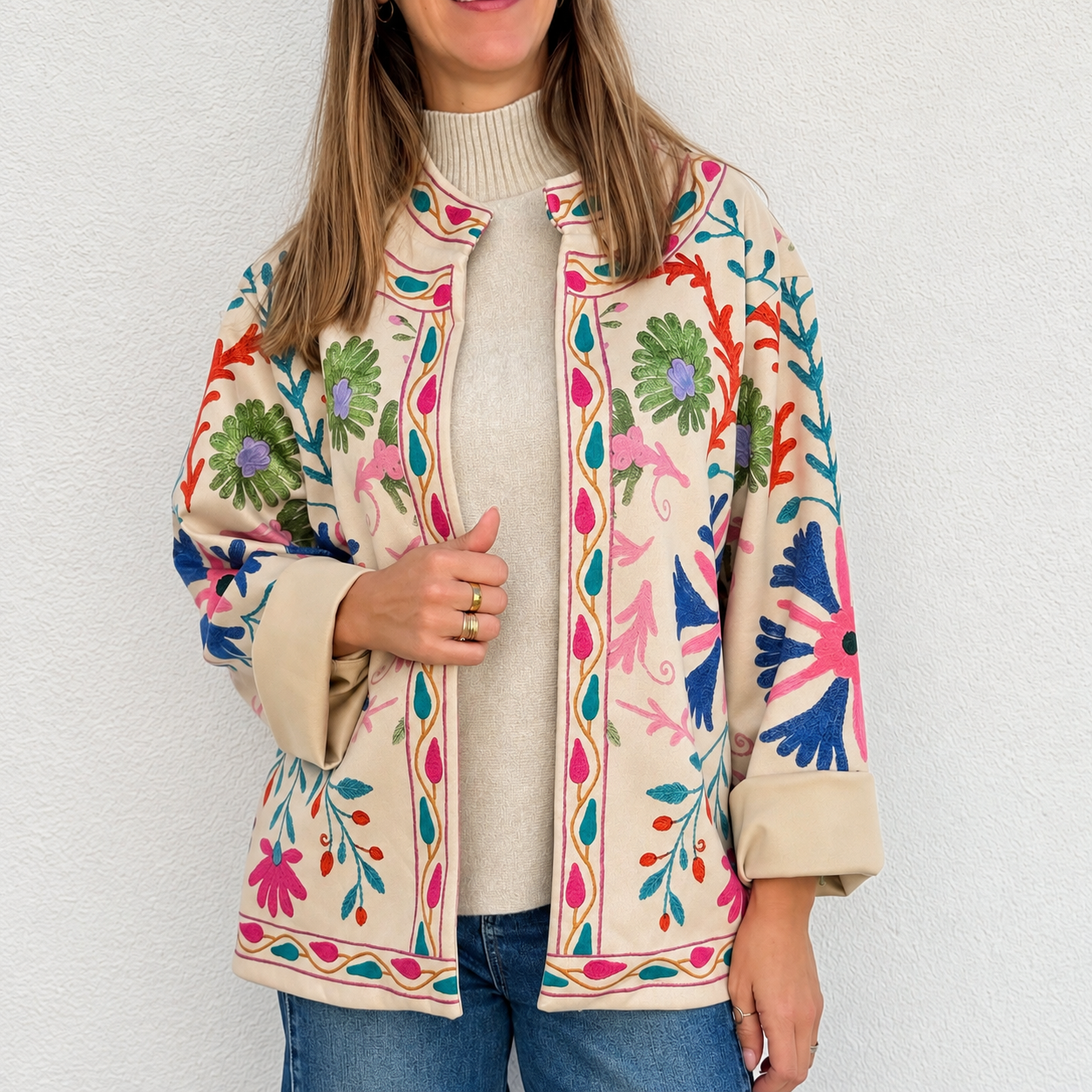 Casaco bege bordado floral colorido com camisola creme e calças de ganga