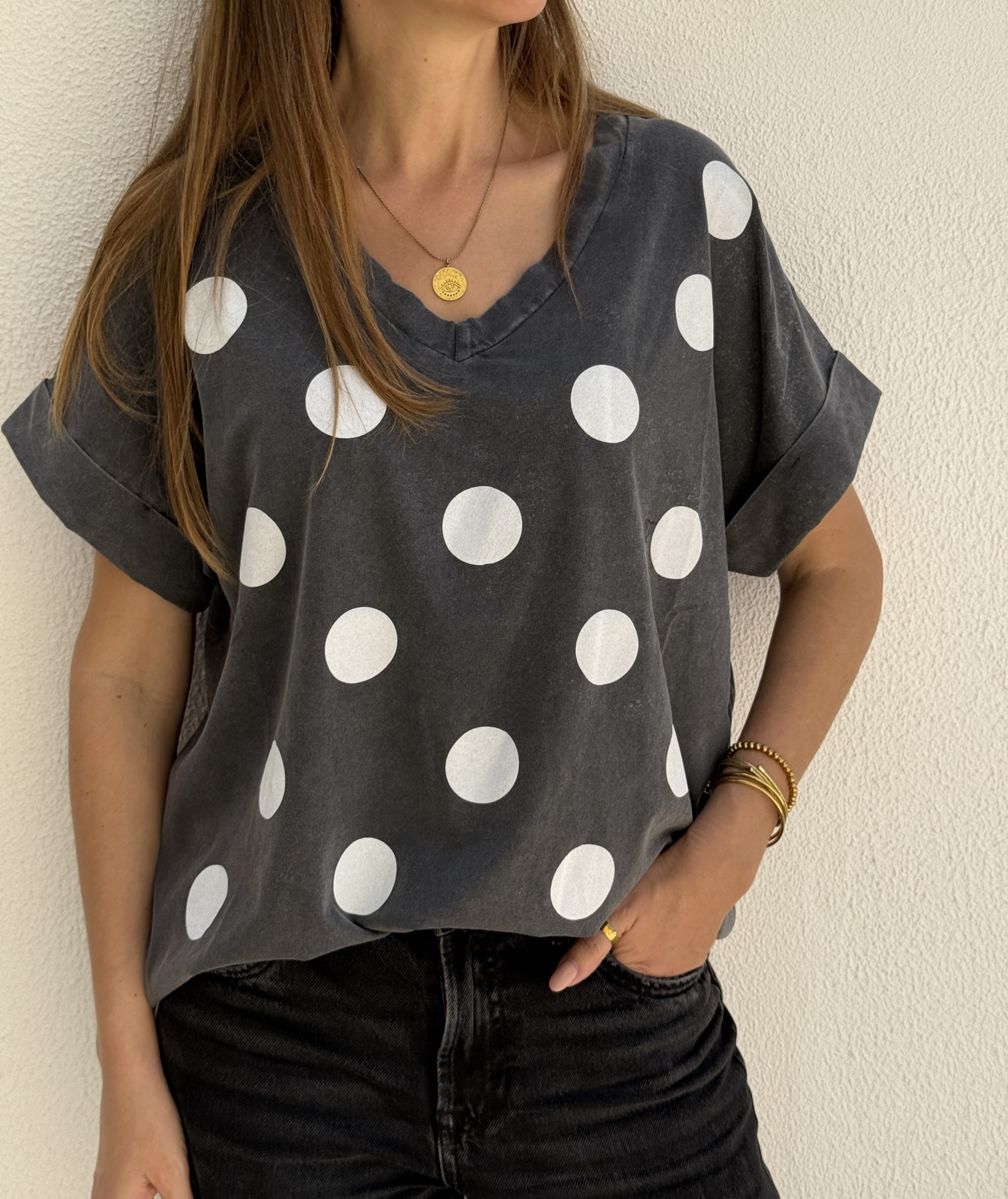 T-shirt cinza escuro com bolinhas brancas e gola em V com mangas dobradas