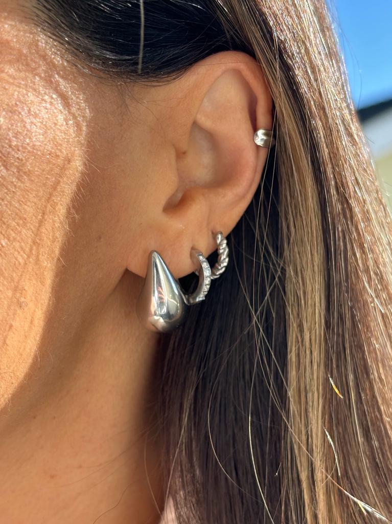 Brincos de prata em orelha feminina com fundo ao ar livre