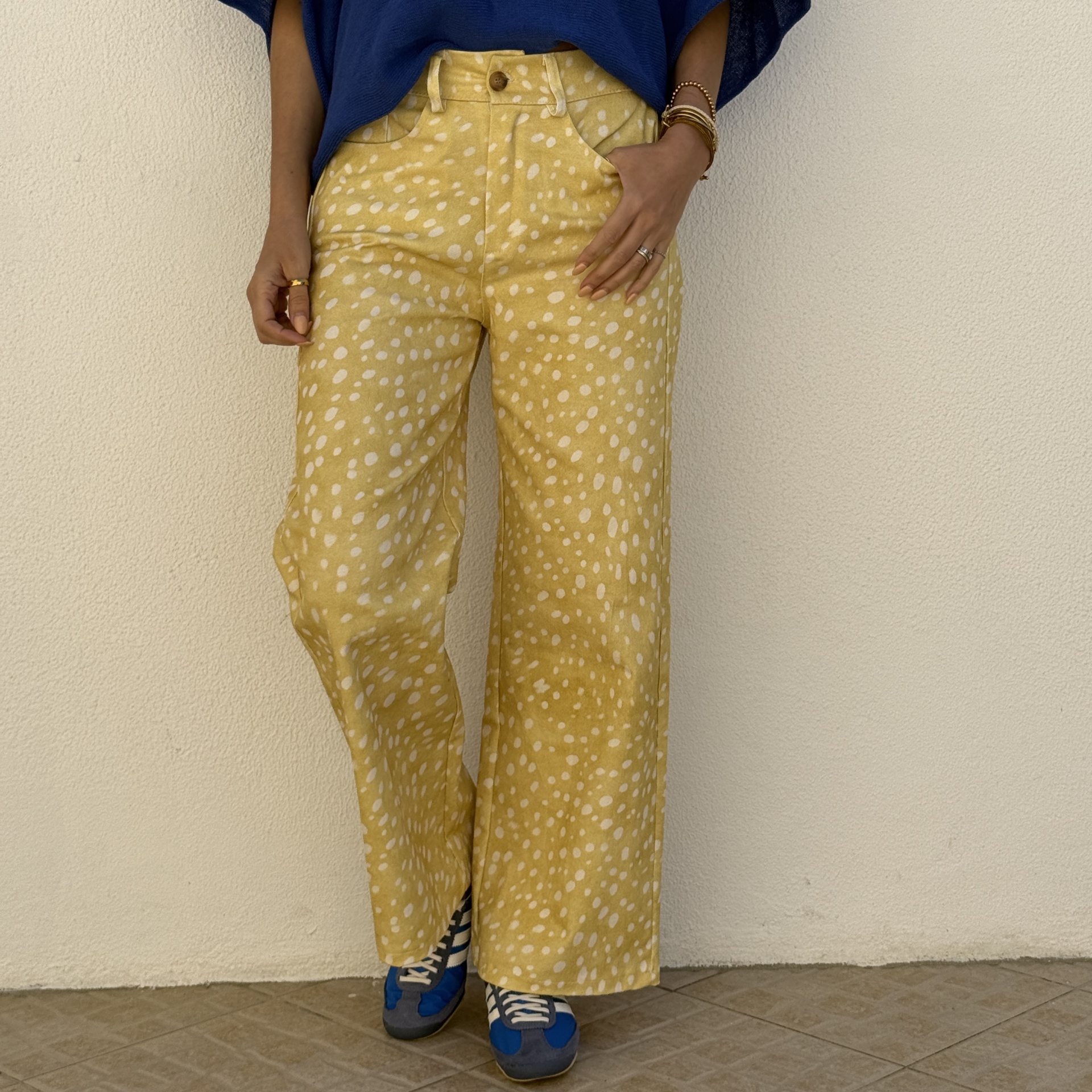 Calças amarelas com manchas brancas e sapatilhas azuis
