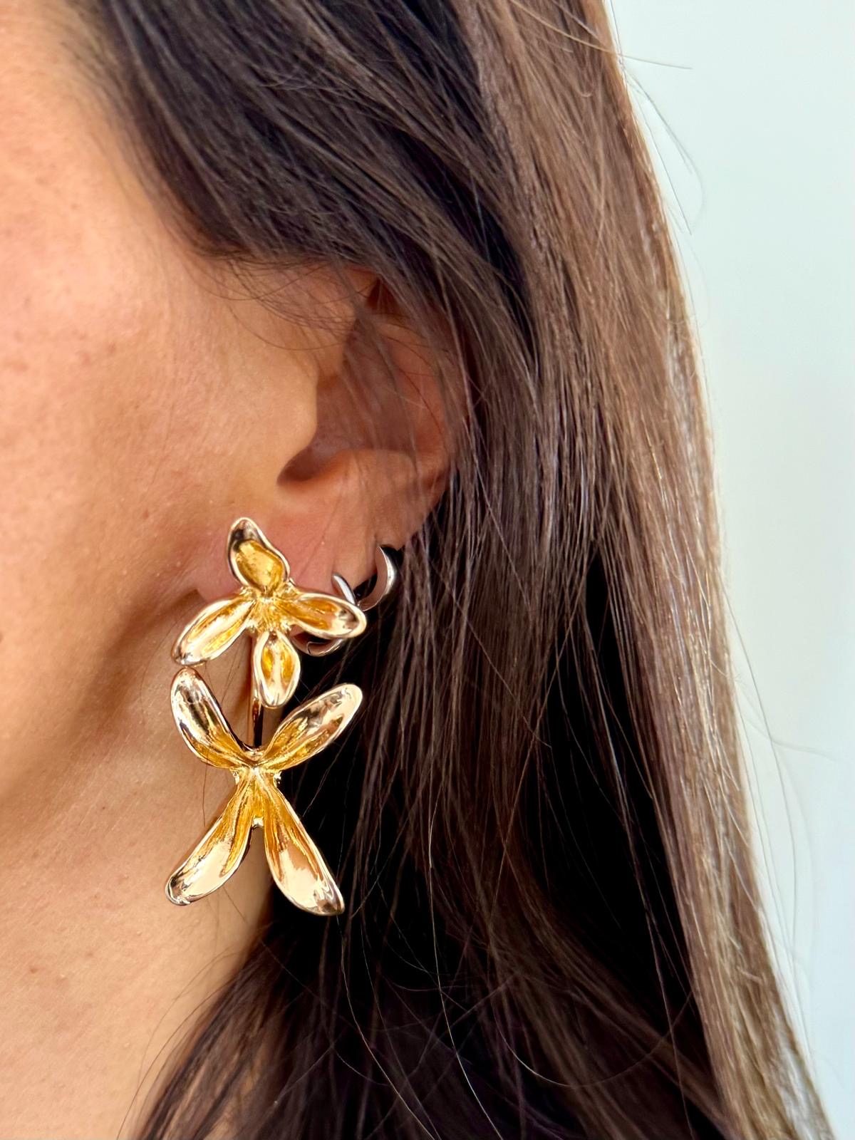 Brincos dourados de flores penduradas na orelha