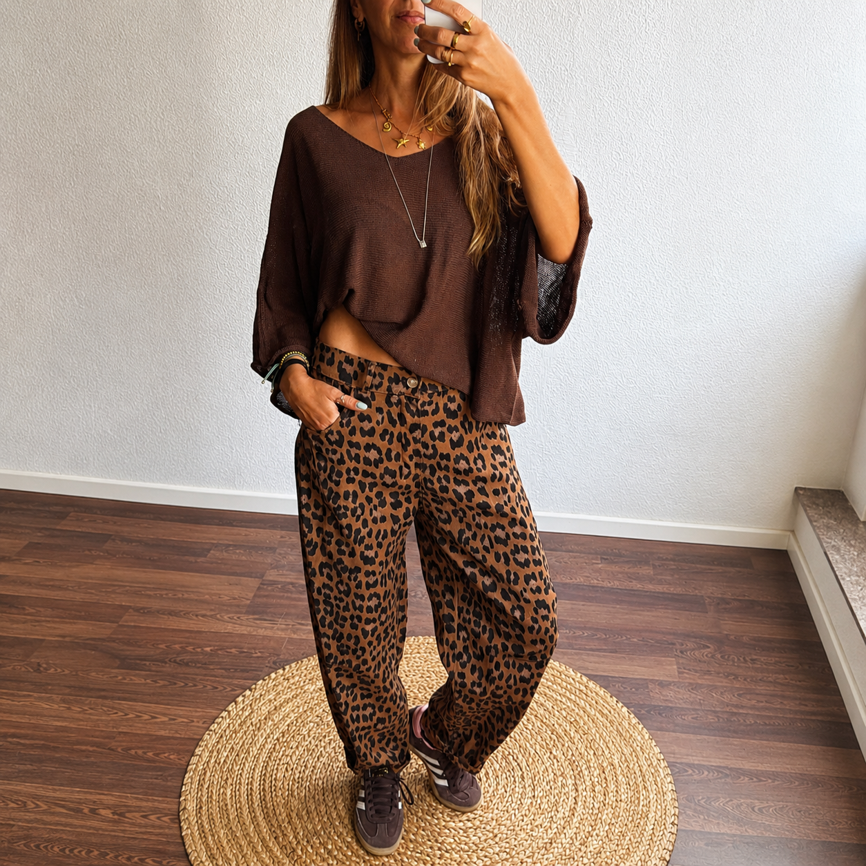 Mulher com camisola castanha e calças animal print
