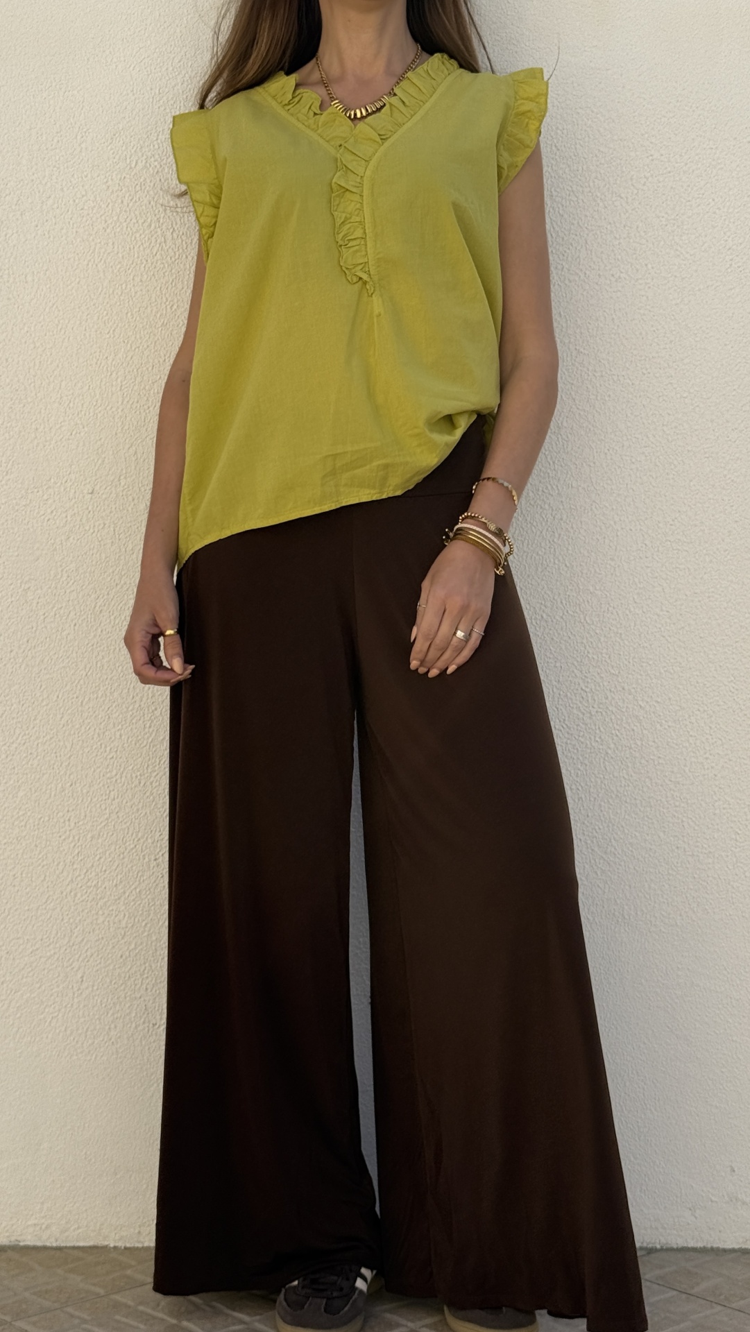 Top amarelo com folhos e calças largas castanhas escuras