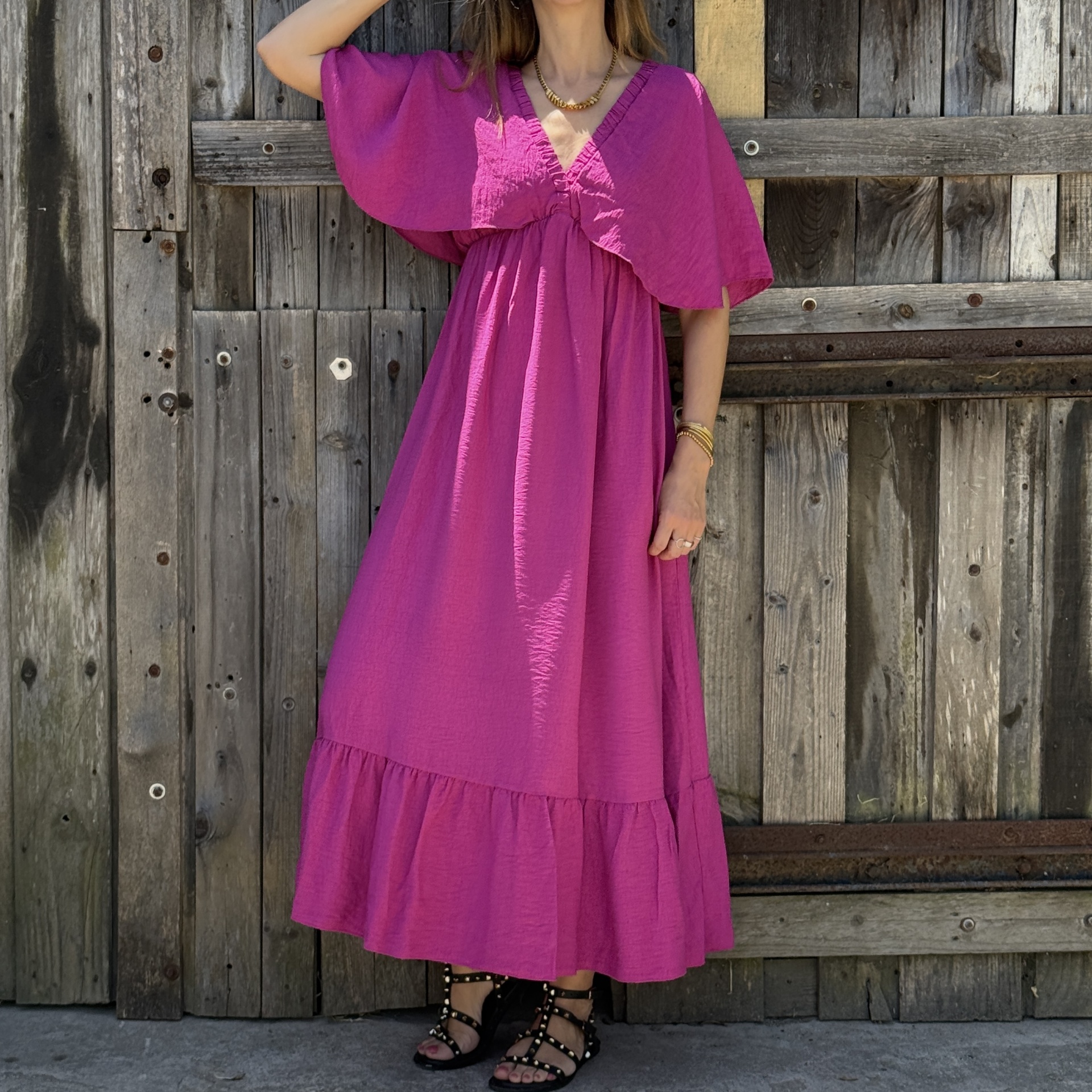 Vestido longo fúcsia com mangas estilo capa e sandálias pretas com tachas douradas