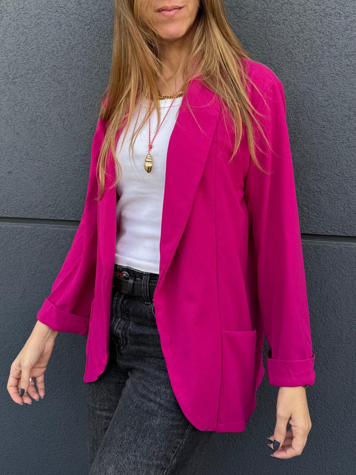 Blazer rosa vibrante feminino com lapela e bolsos, usado com t-shirt branca e jeans pretos