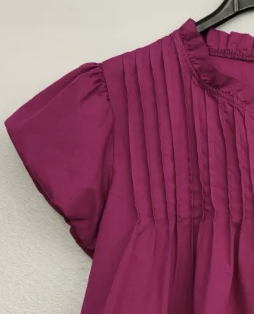 Peça de roupa vinho com mangas bufantes e pregas verticais