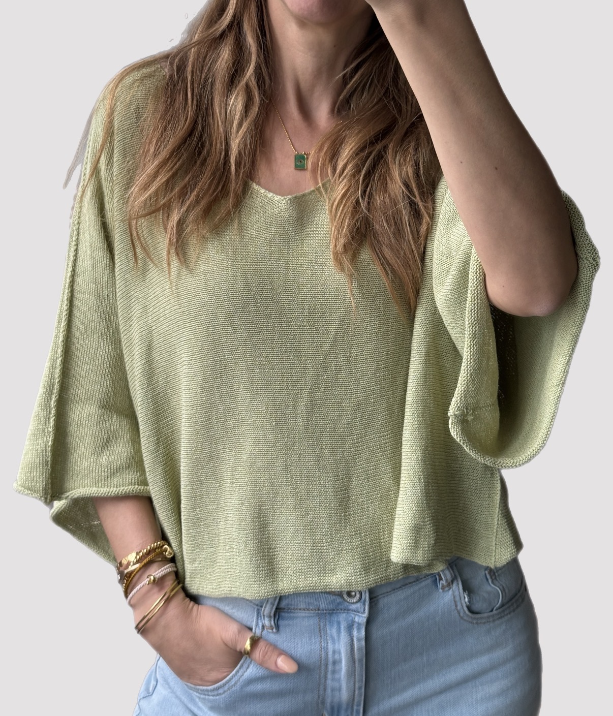 Camisola verde claro de malha com mangas largas e calças de ganga azuis claras