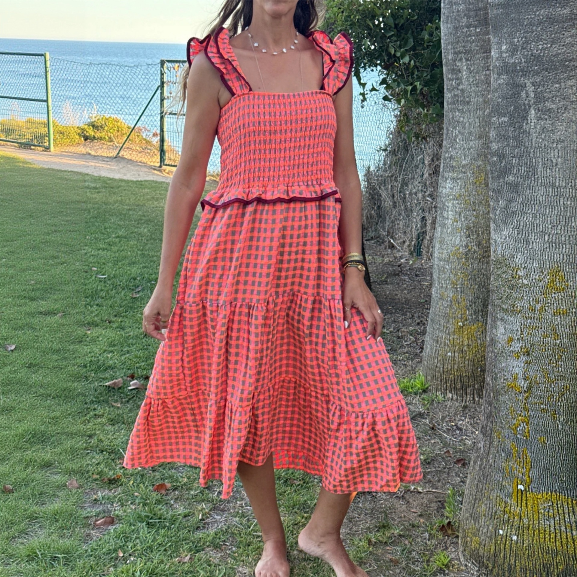 Vestido feminino vermelho e rosa com padrão xadrez e detalhes em carrinho