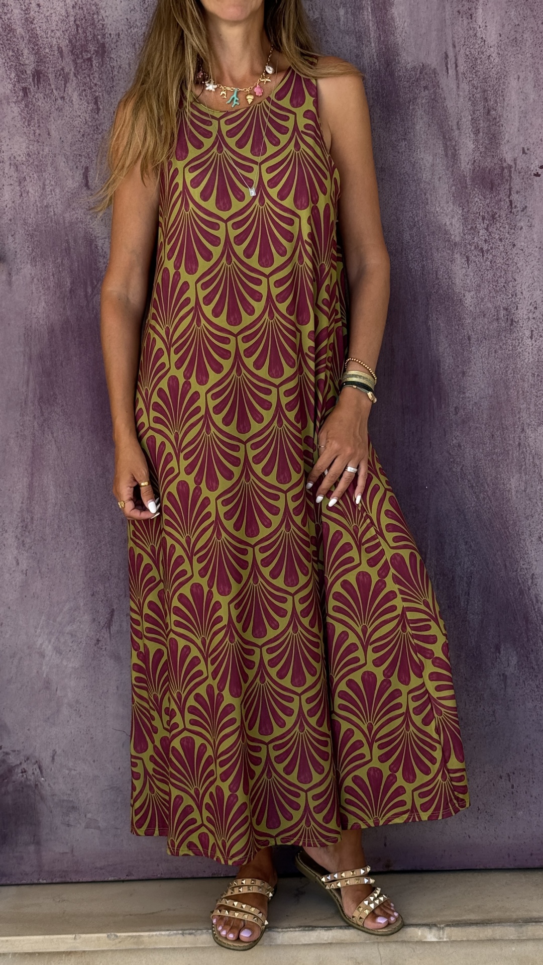 Vestido comprido bege com padrão roxo, sandálias douradas e colar colorido
