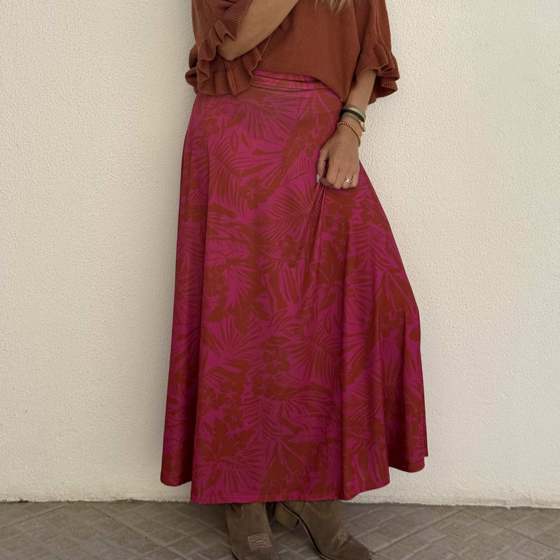 Saia midi rosa e vermelha com padrão floral e botas castanhas de camurça