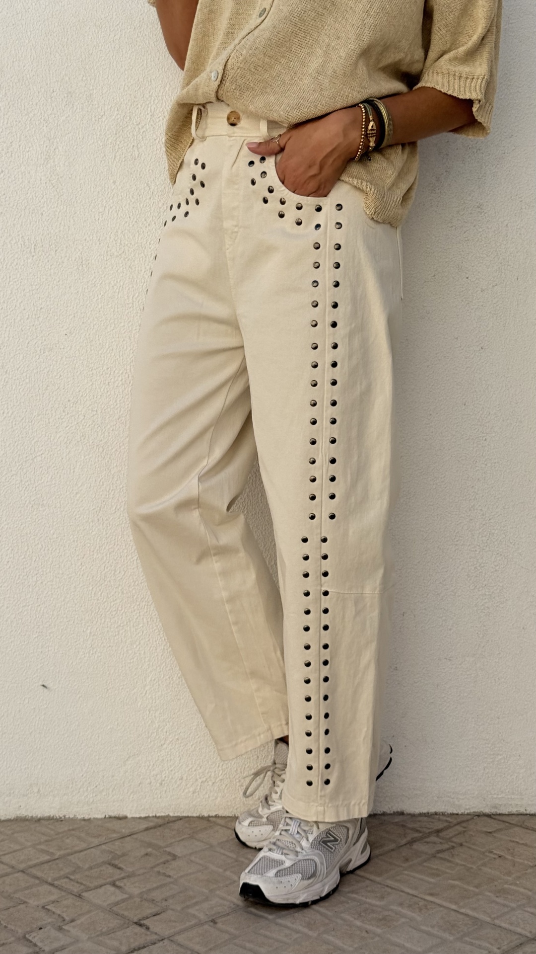 Calças creme com tachas pretas e sneakers brancos
