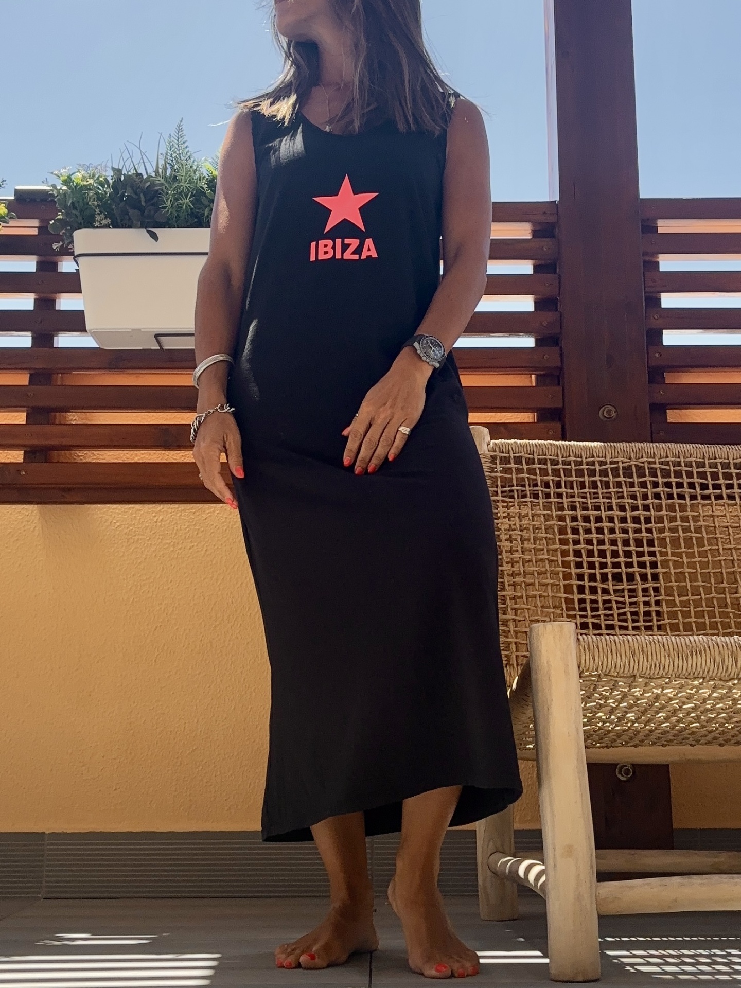 Vestido preto com estampa vermelha IBIZA usado numa varanda com cadeira de vime