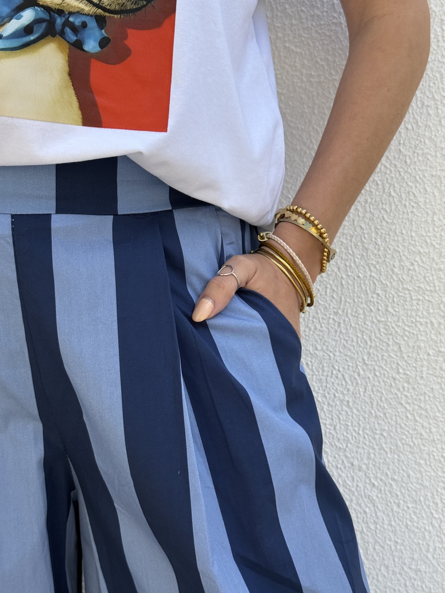 Calças de riscas azuis com t-shirt branca e pulseiras douradas