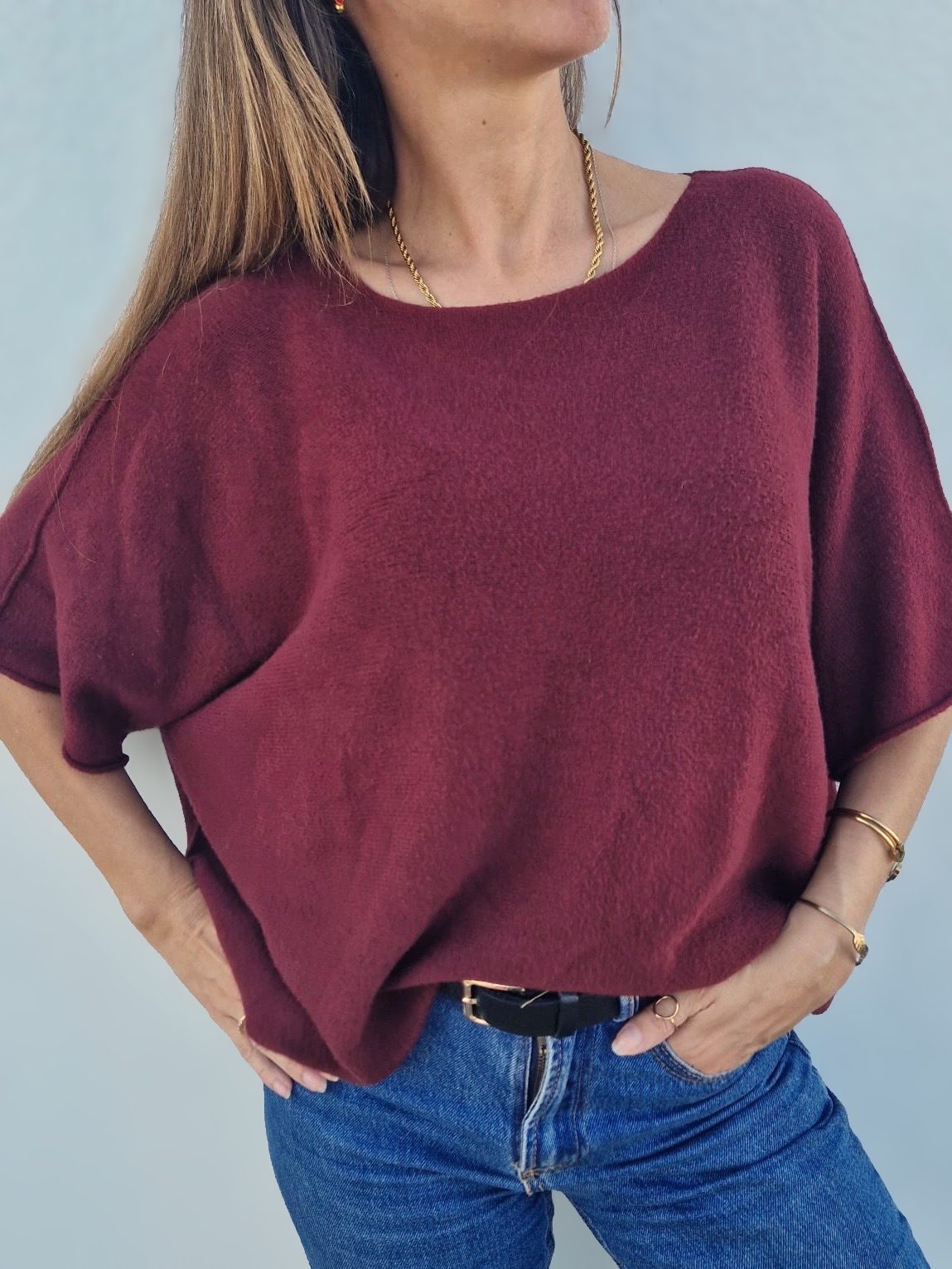 Camisola bordô de malha com decote redondo e mangas curtas largas combinada com jeans azul
