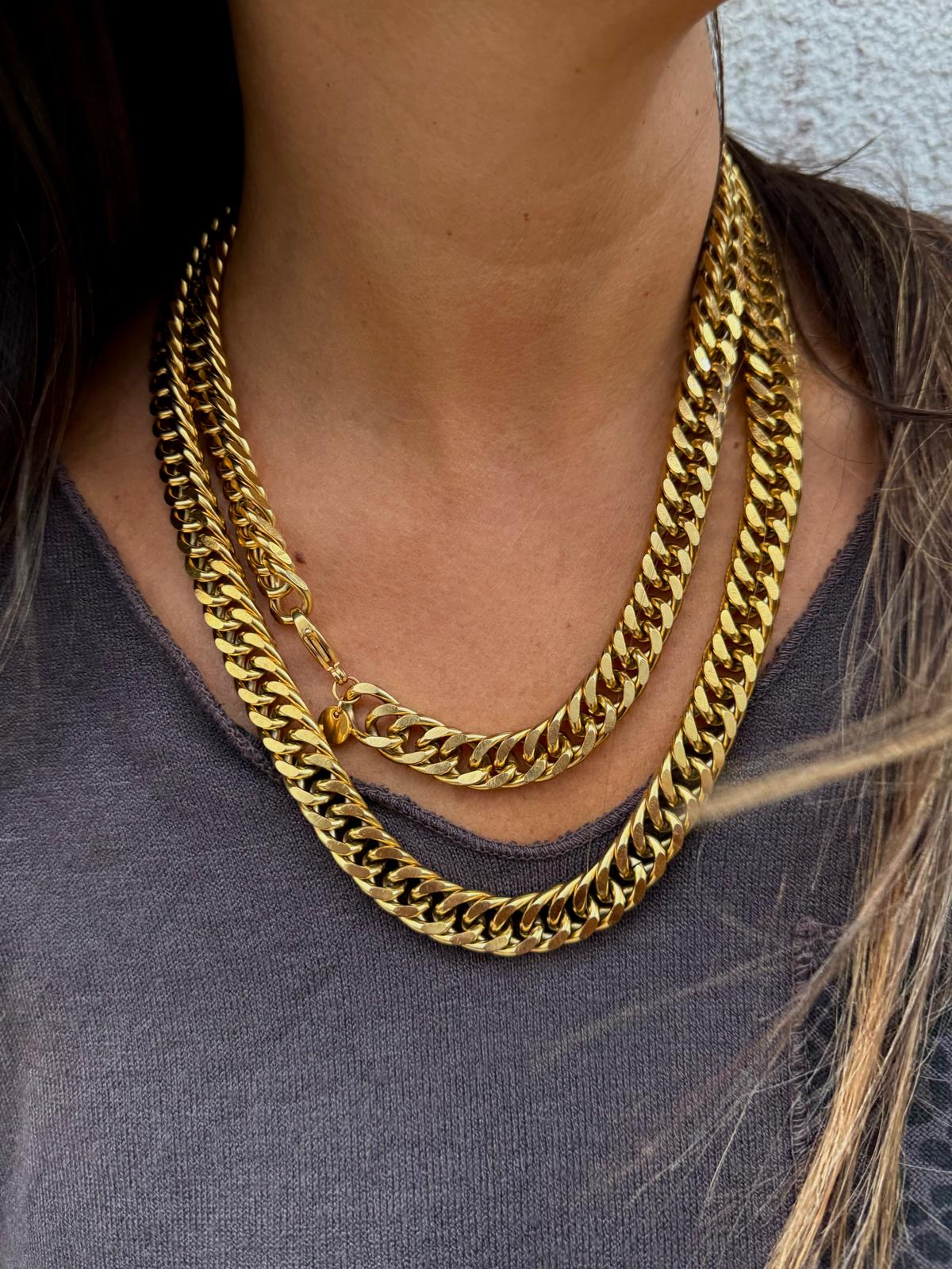 Colar de corrente grossa dourada em duas voltas numa pessoa com camisola cinza escura