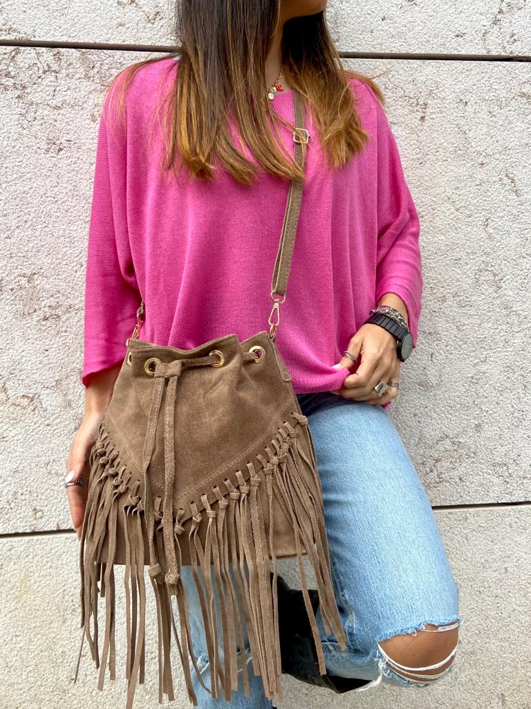 Saco castanho de camurça com franjas, mulher com camisola rosa e calças de ganga rasgadas