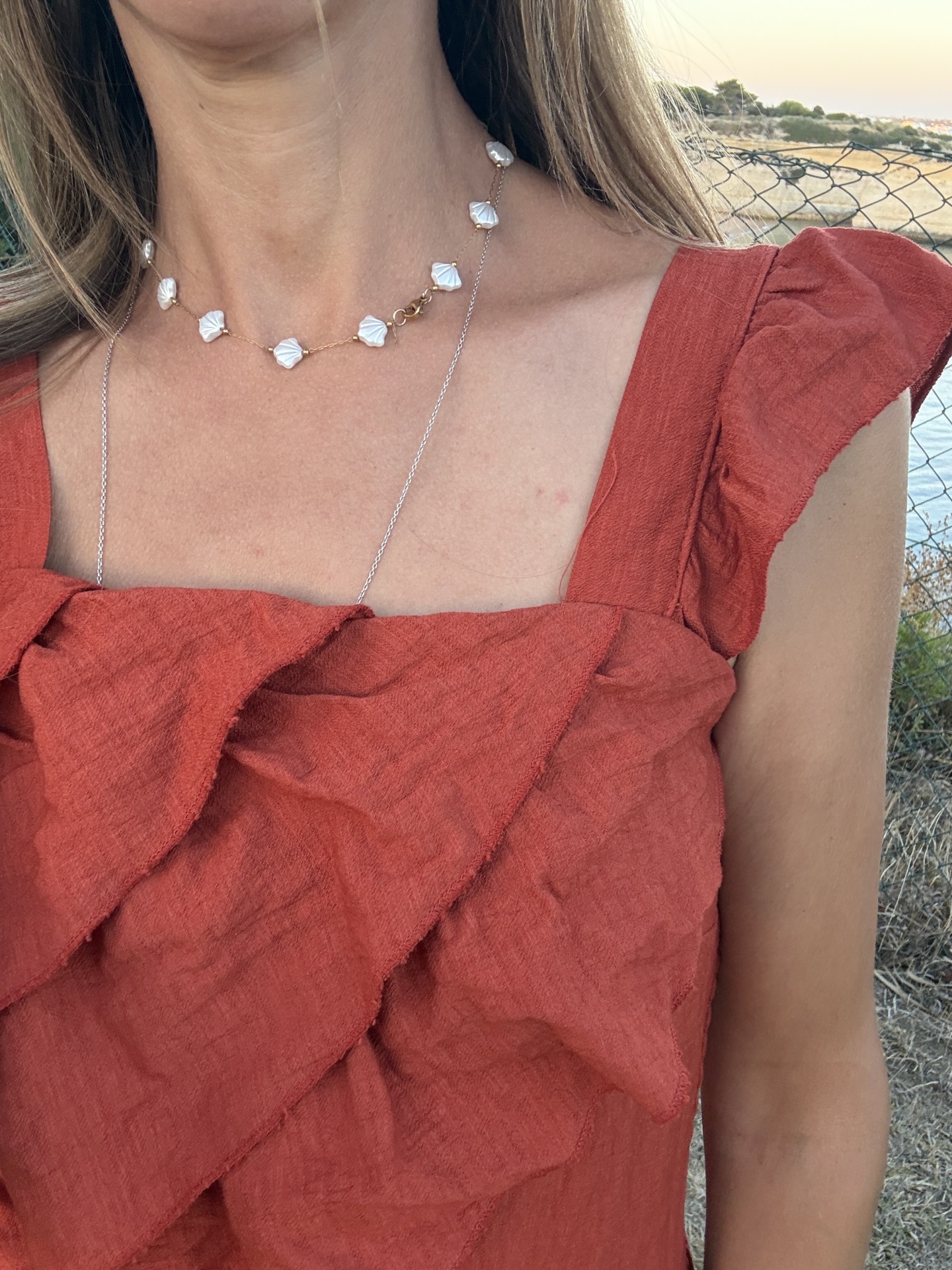 Colar curto com contas brancas em forma de concha e vestido vermelho com folhos
