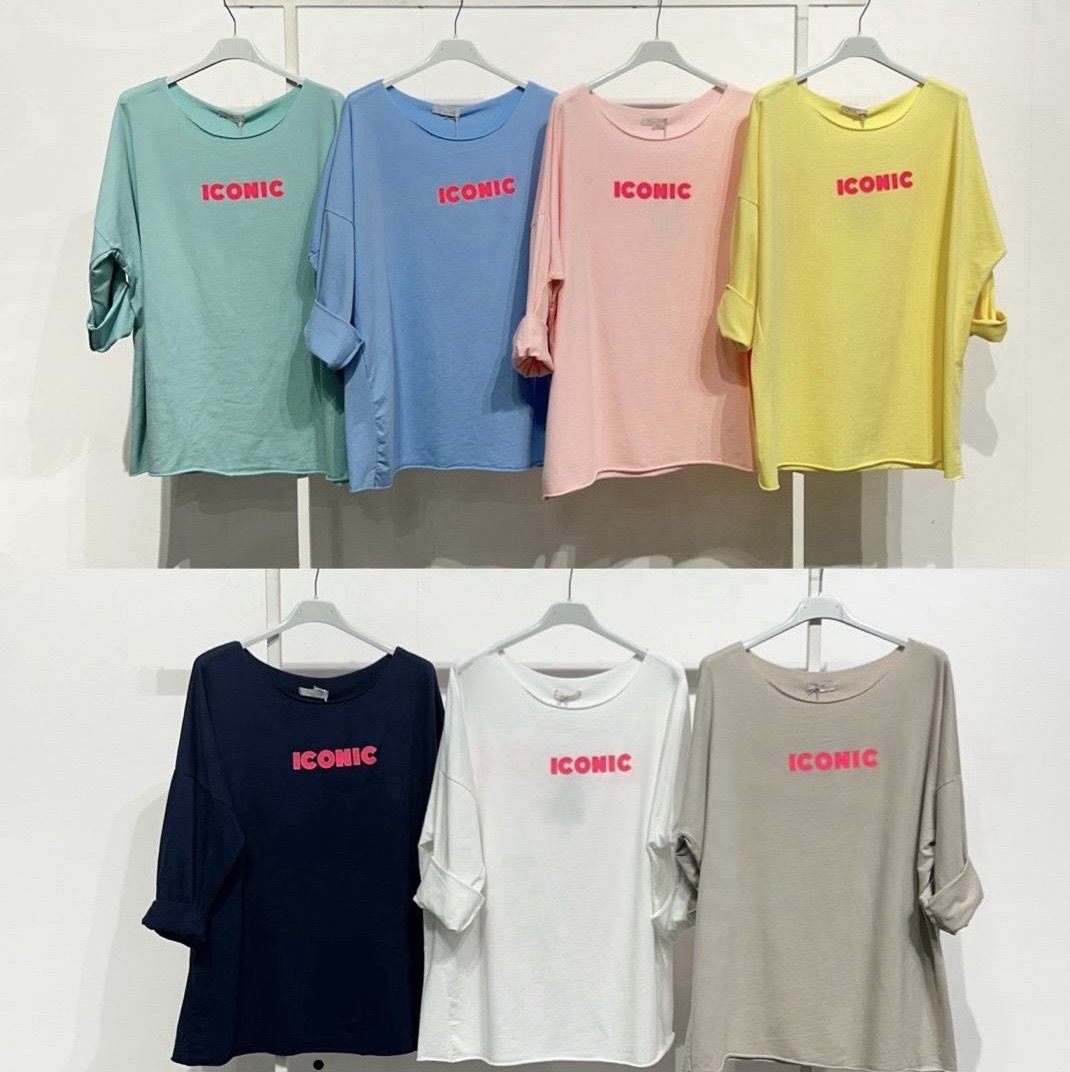 Camisolas de manga comprida coloridas com a palavra ICONIC em vermelho penduradas numa parede branca