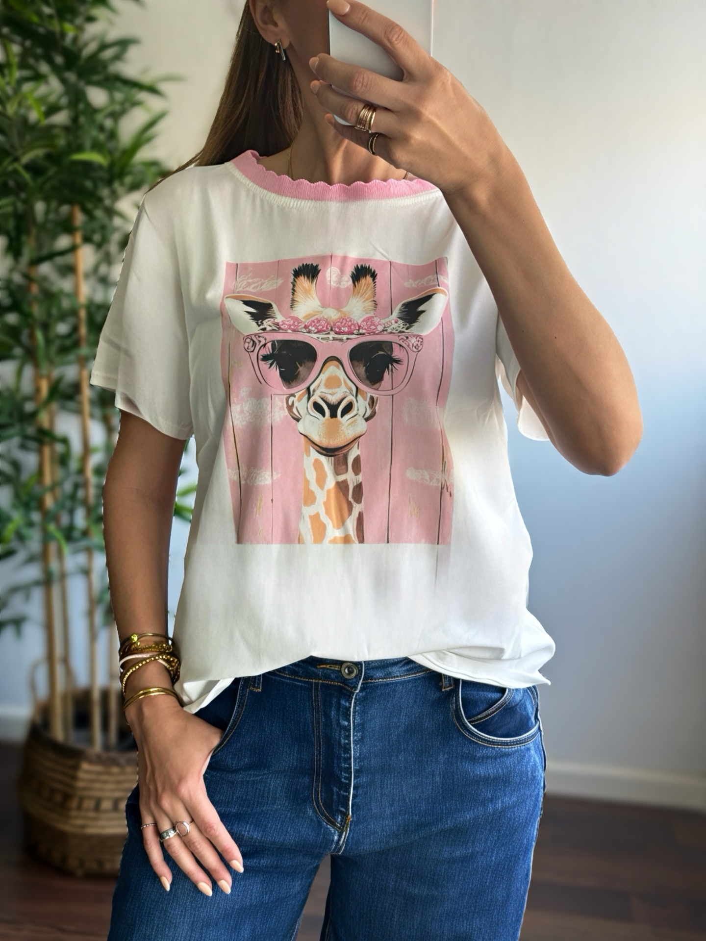 T-shirt branca com estampado de girafa usando óculos cor-de-rosa