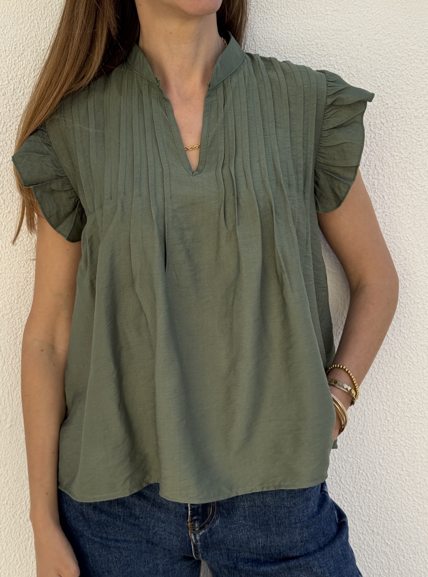 Blusa verde com mangas franzidas e decote em V vestida por mulher