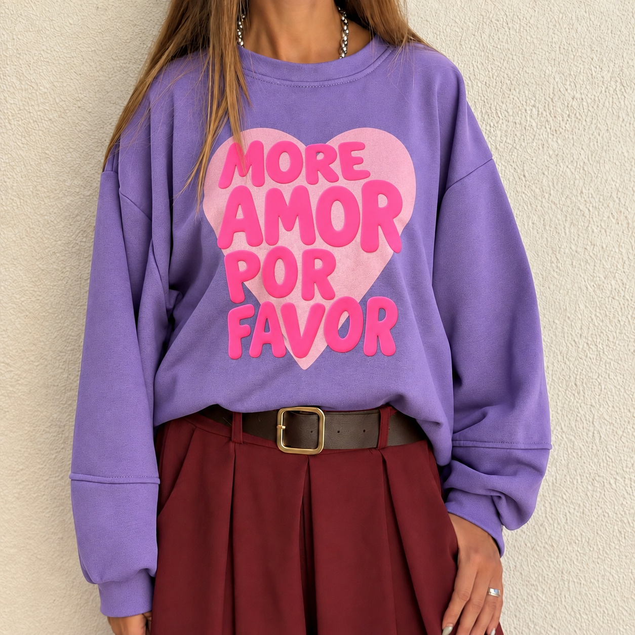 Sweatshirt roxa com coração rosa e texto MORE AMOR POR FAVOR, saia bordô e cinto castanho.