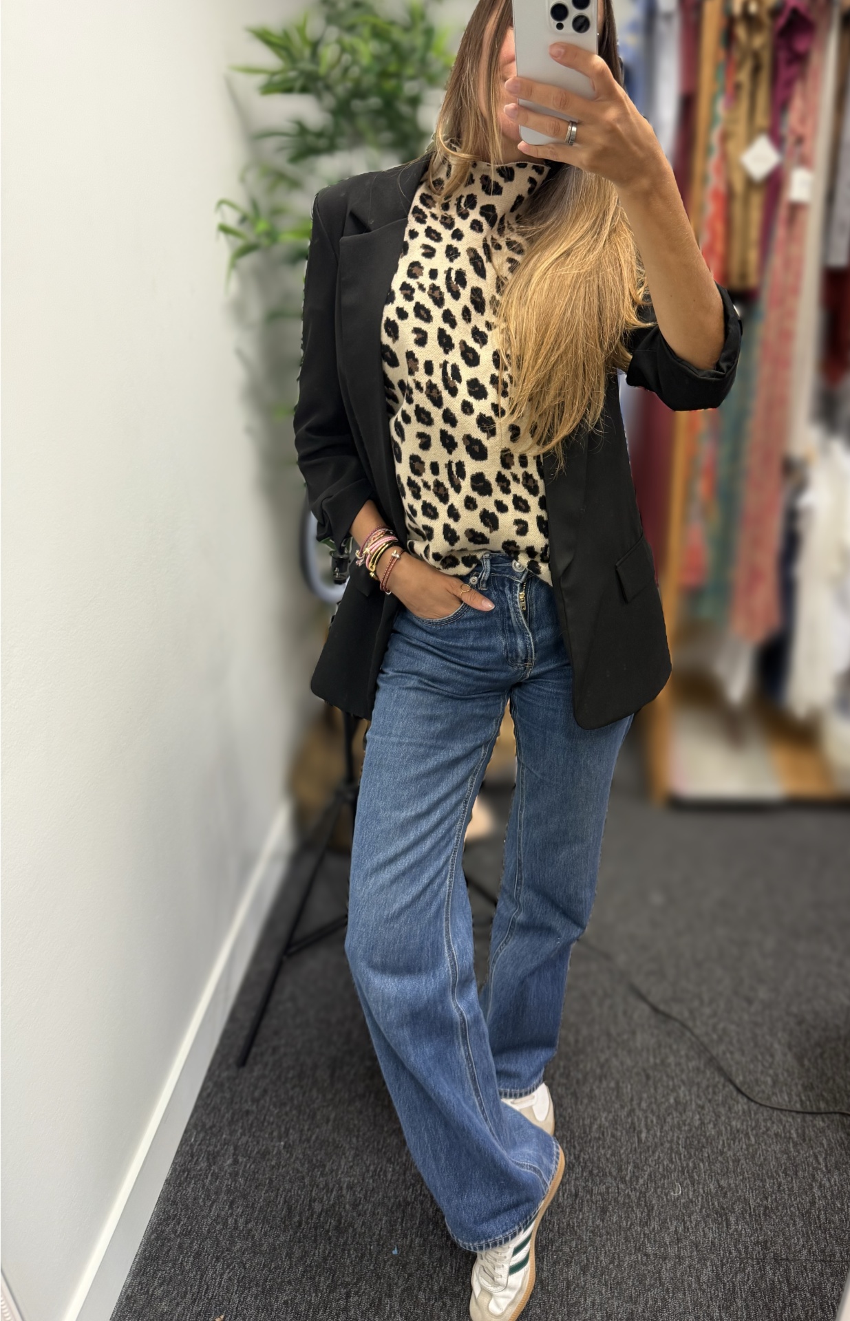 Mulher com blazer preto, camiseta animal print, jeans azuis e ténis brancos
