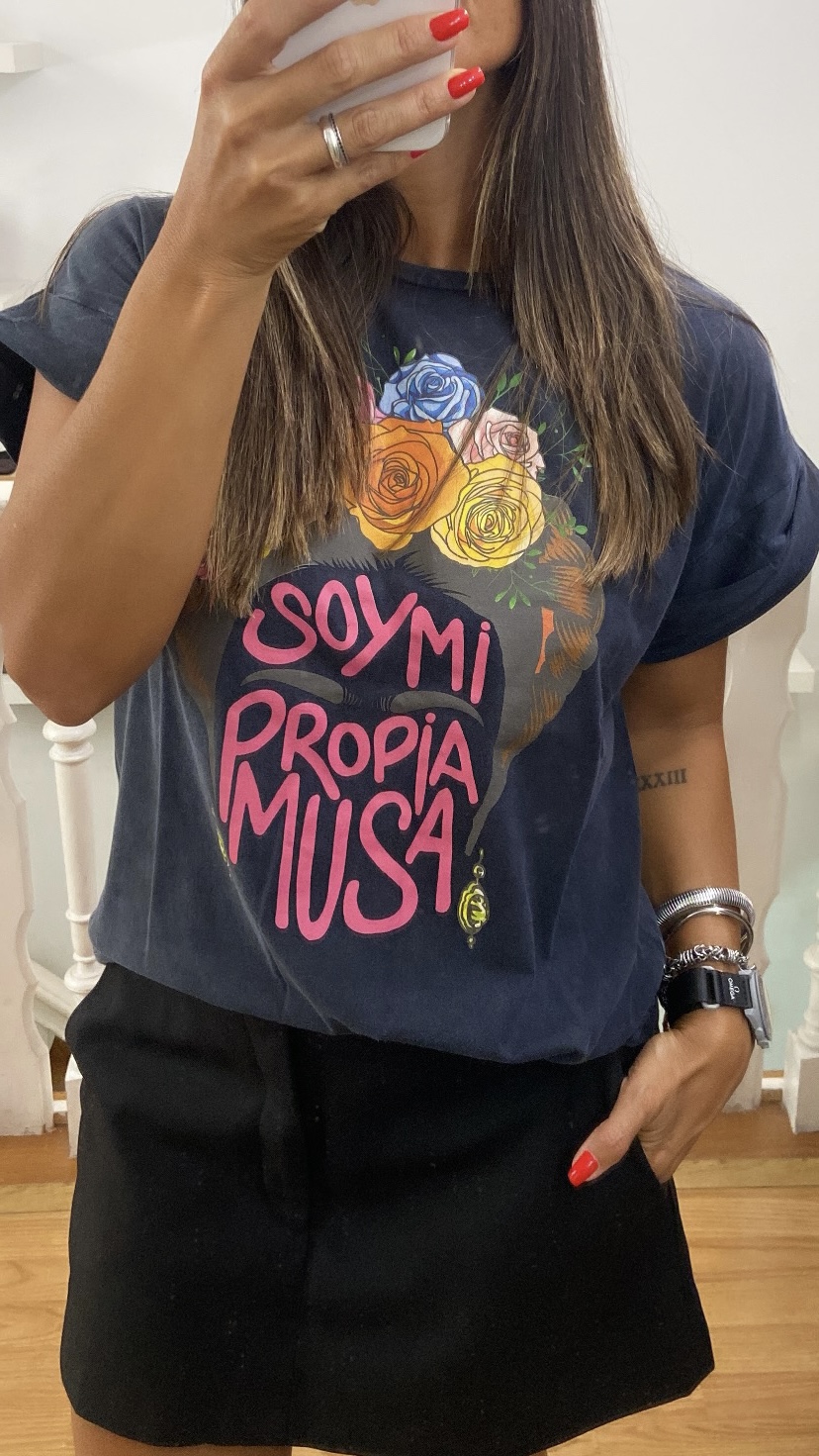 T-shirt preta com flores coloridas e texto em rosa, usada com saia preta.