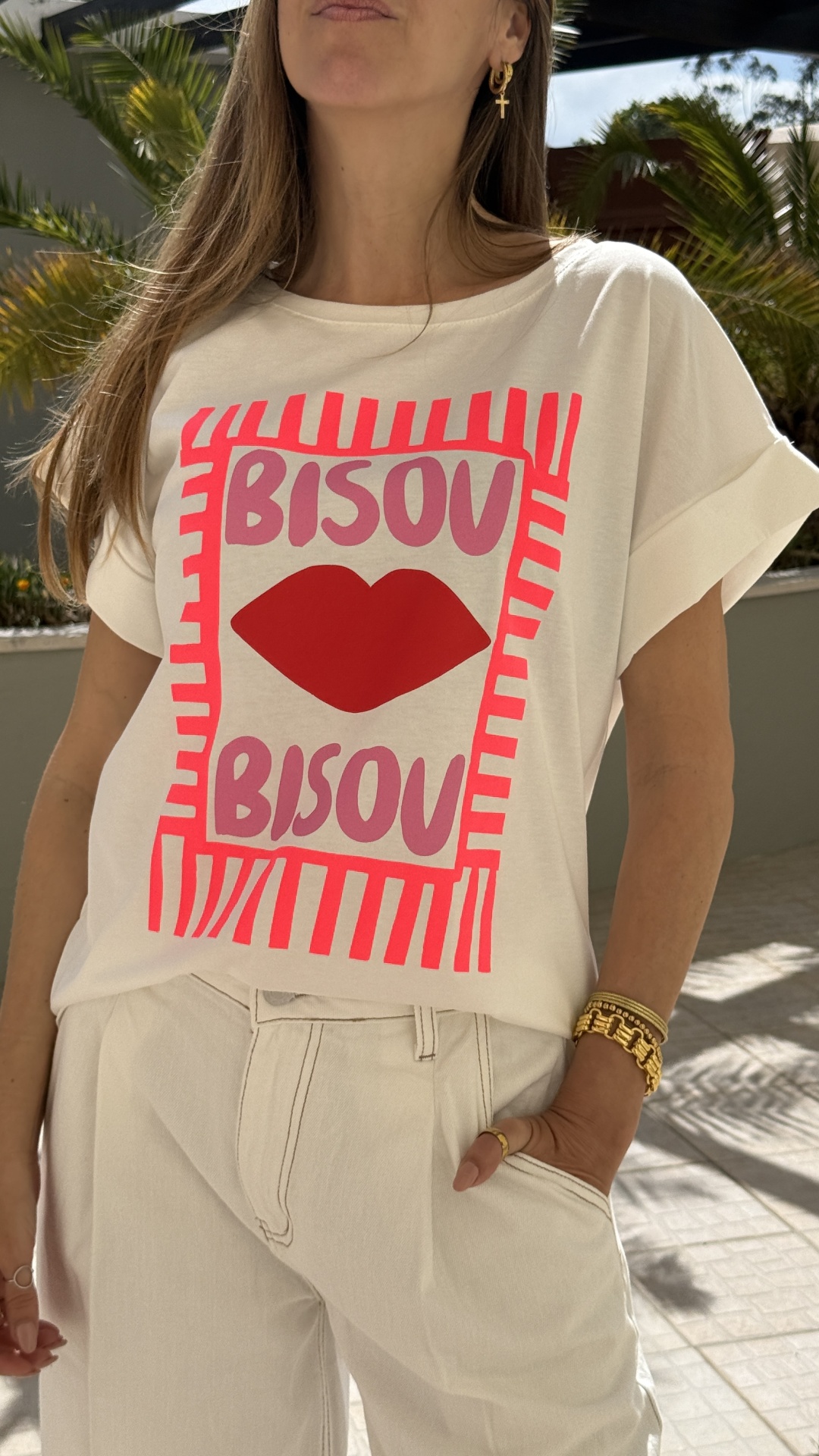 T-shirt branca com estampa rosa e vermelha BISOU e lábios vermelhos, calças brancas com costuras visíveis