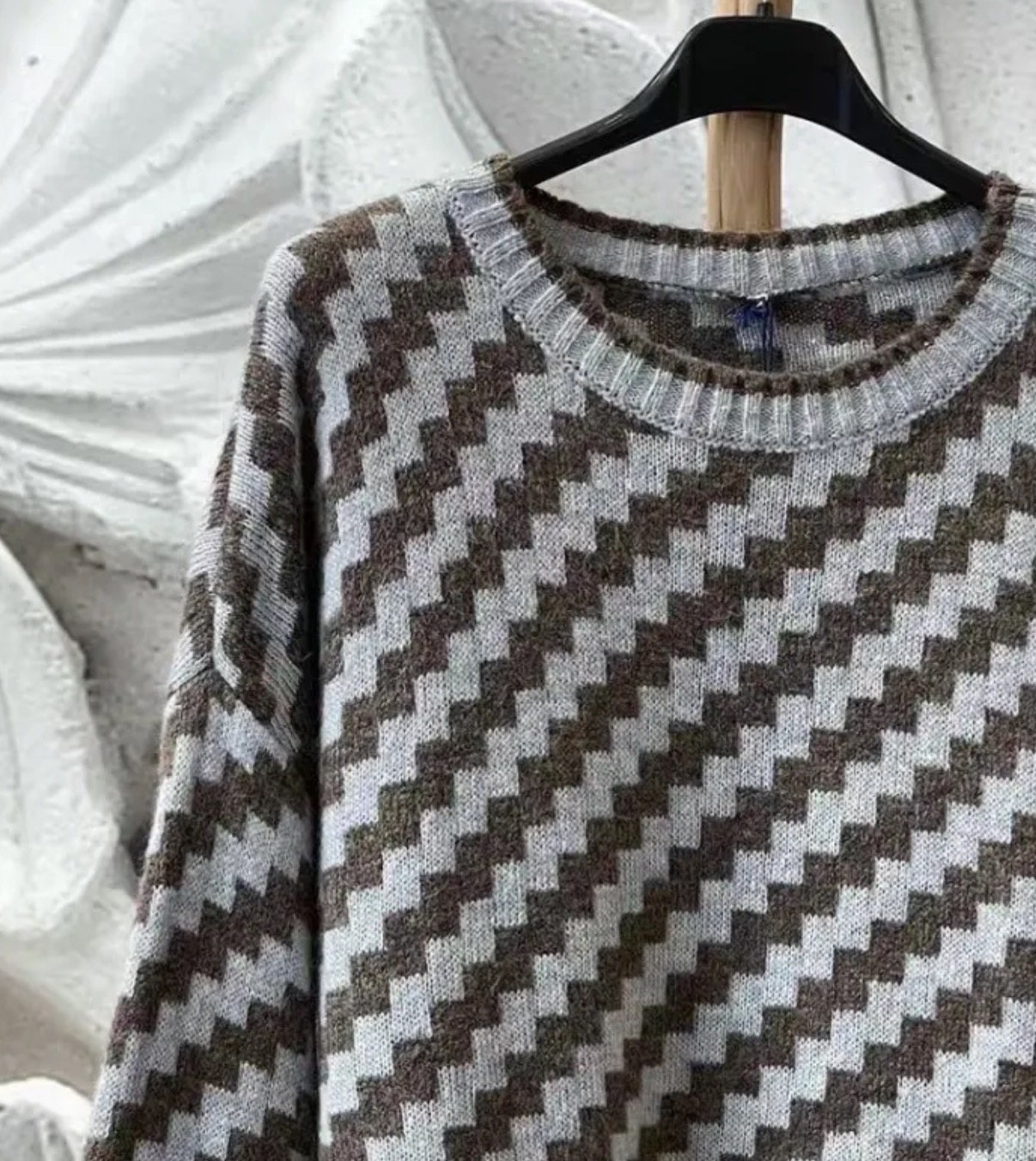 Camisola de malha com padrão geométrico em zig-zag castanho, verde e cinza num cabide preto